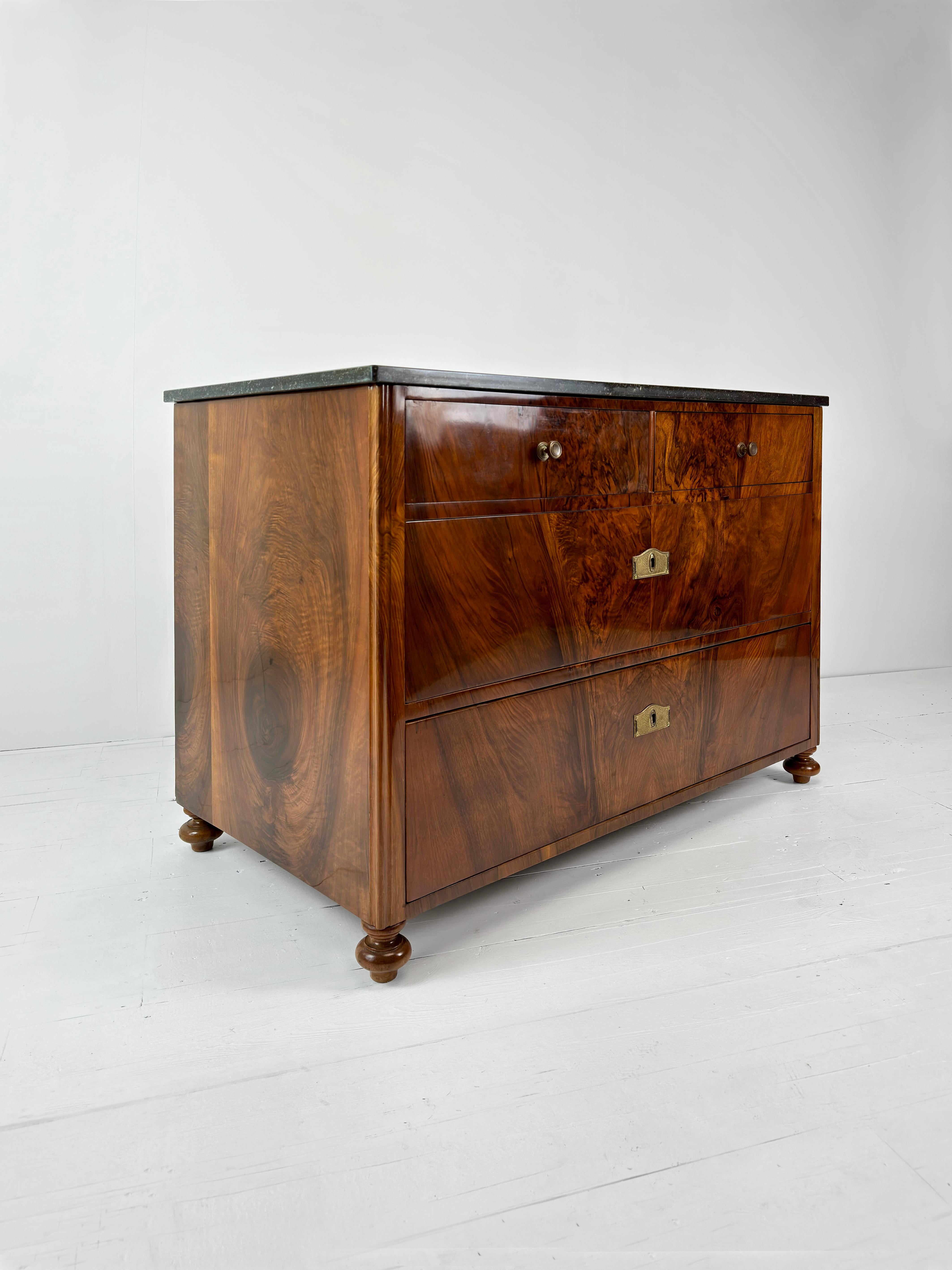An absolutely stunning example of an Art Deco French Commode, in a highly character grain walnut timber. The marble top id a green with white speckled variety and the feet are also turned timber. The keyholes for the two wide drawers have Brass