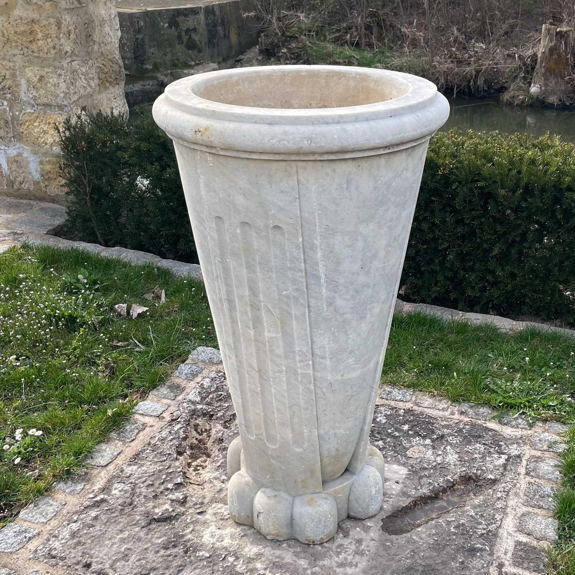 Large conical vase made of gray marble with fluted pilasters and a round base.