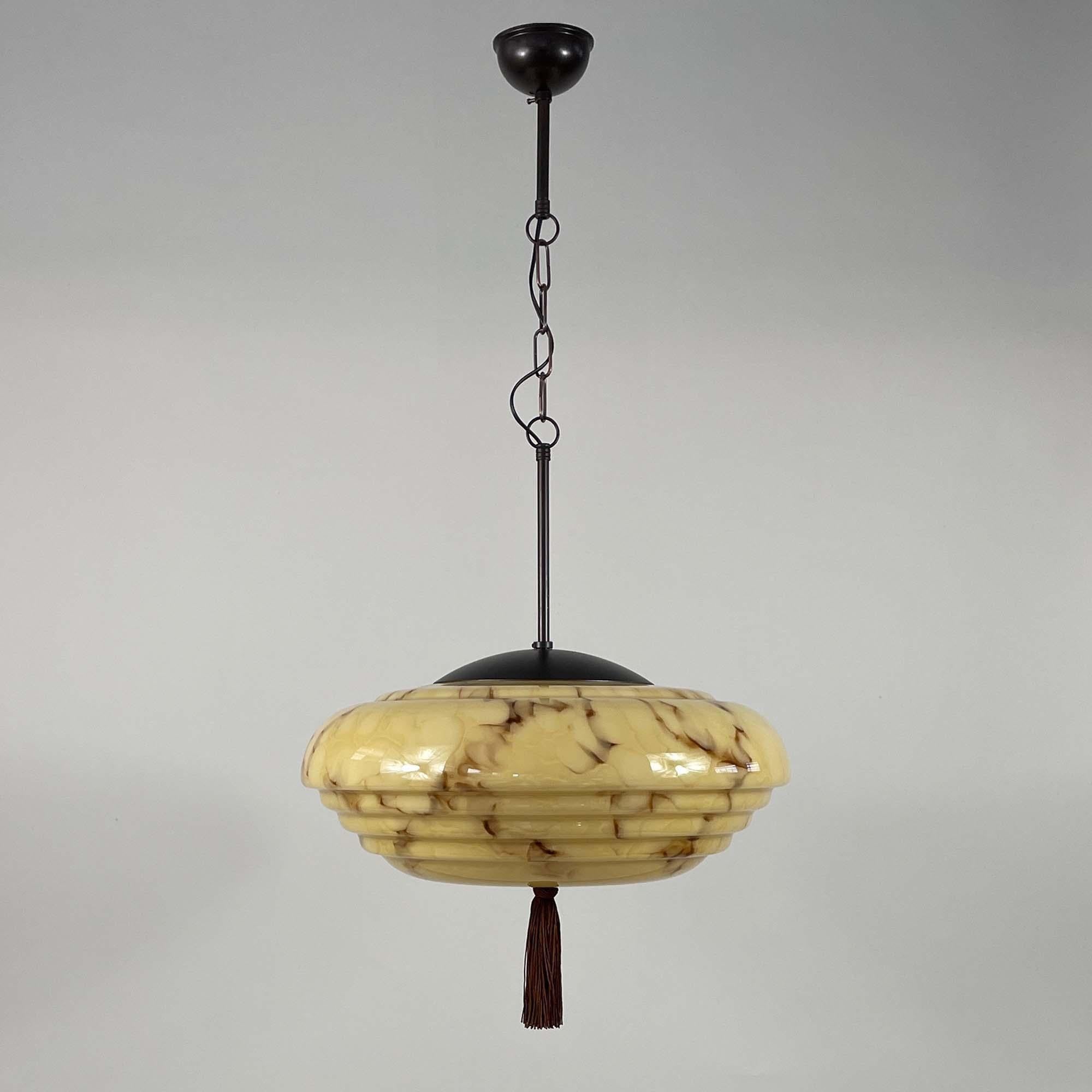 This unusual large pendant was designed and manufactured in Germany during the Bauhaus Period in the 1920s to 1930s.

It features a large dark cream / sand colored opaline glass lampshade with brown marbled decor, bronzed / burnished metal hardware