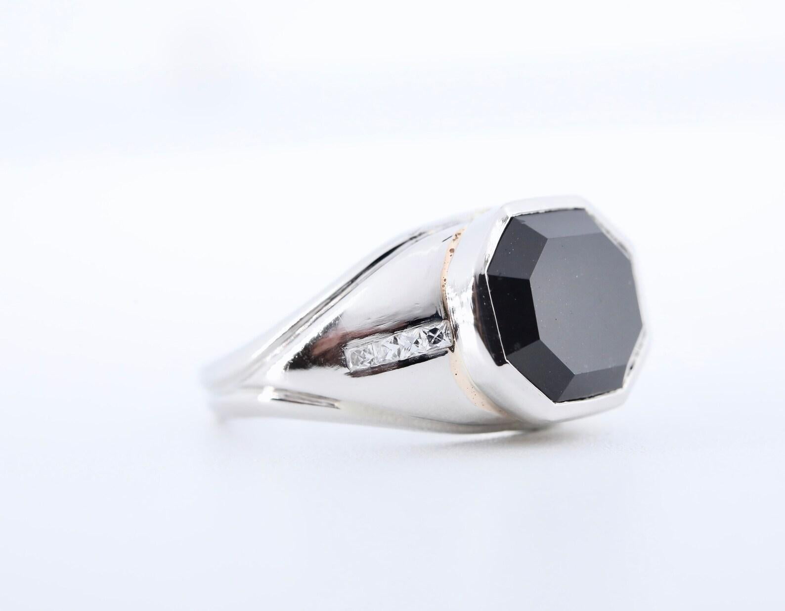 An Art Deco period unisex ring in platinum by Marcus & Co.

Centered by a rectangular step cut black spinel measuring 11mm by 9mm set in a polished platinum bezel.

Framing the black spinel are eight French cut diamonds of 0.32ctw with G color and