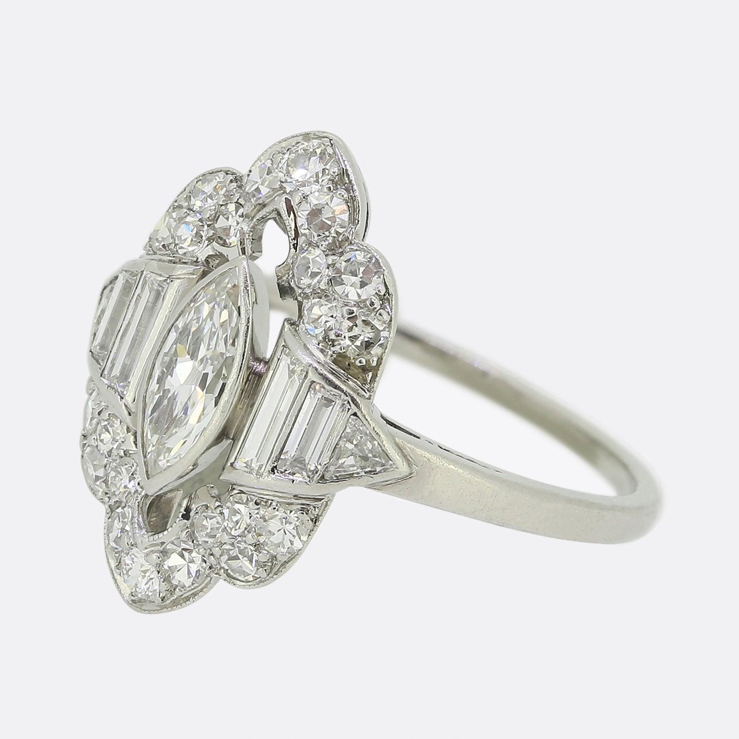 Here we have an elegant diamond cluster ring. This original Art Deco piece showcases a single marquise cut diamond at the centre of the face which is flanked on either side by a duo of graduating straight baguette cut diamonds and single triangular