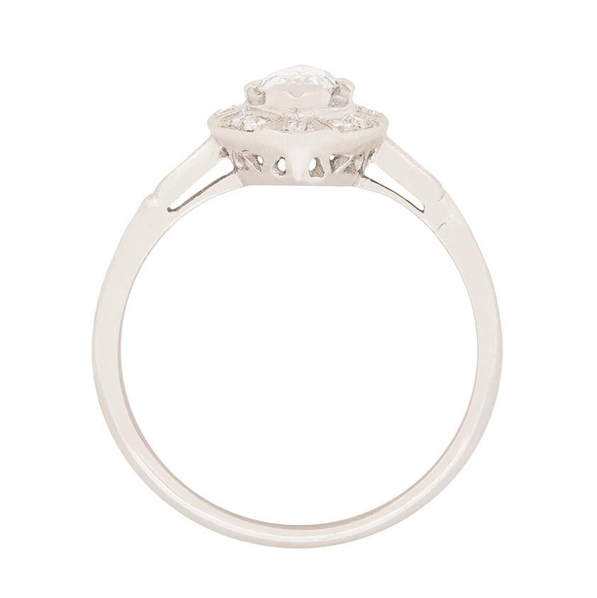 Dating to the 1920s, this solitaire features a rare, old marquise cut, set to centre. The sparkling stone, weighing 0.68 carat has been graded as an F in colour and VS2 in clarity. It is haloed by 12 grain set, 8-cut diamonds, which have a combined