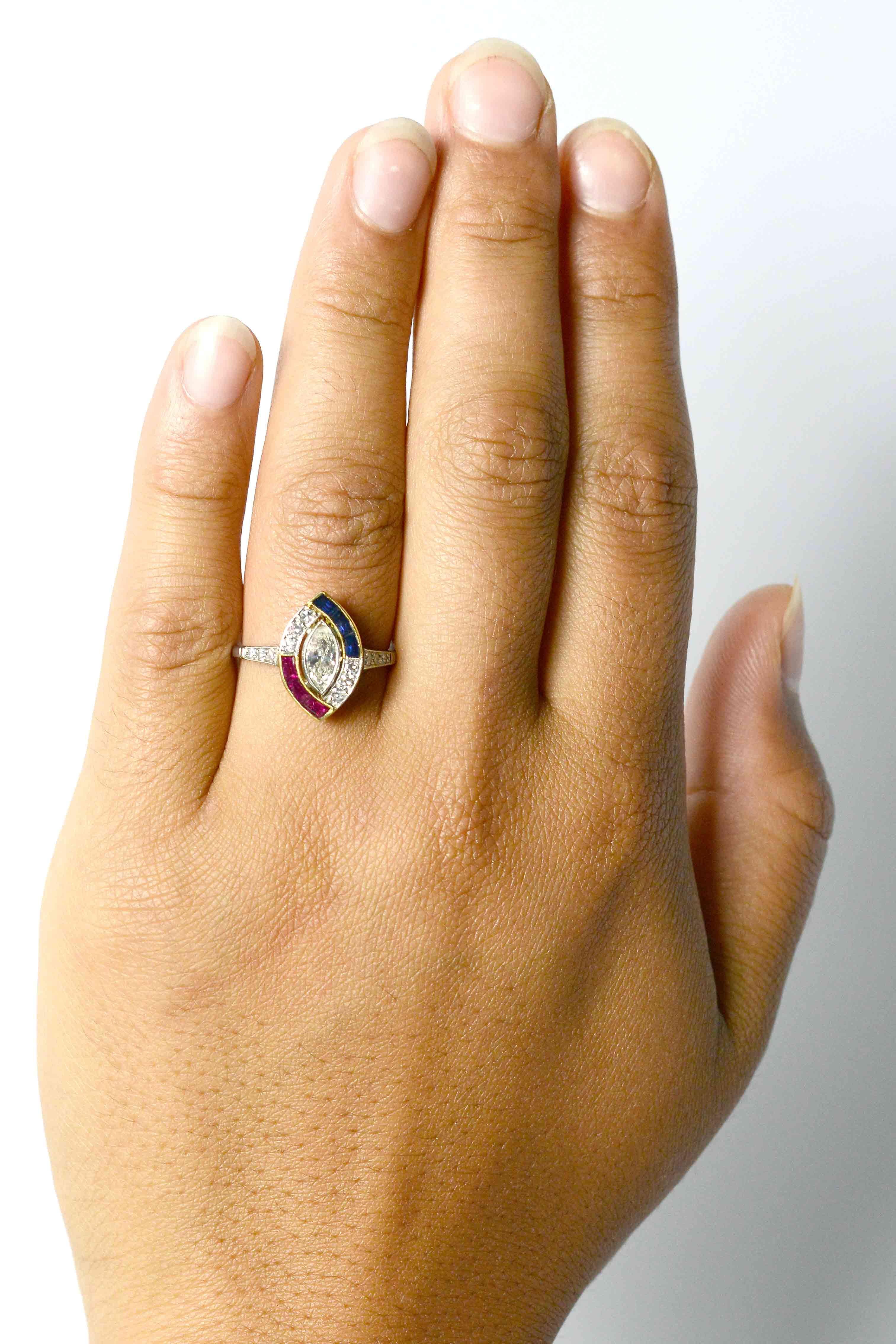The Oceano Art Deco marquise diamond, ruby & sapphire engagement ring with a unique, asymmetrical halo. Centering on a riveting 0.40 carat navette diamond with a captivating brilliance. Held securely by a detailed millegrain platinum bezel, framed