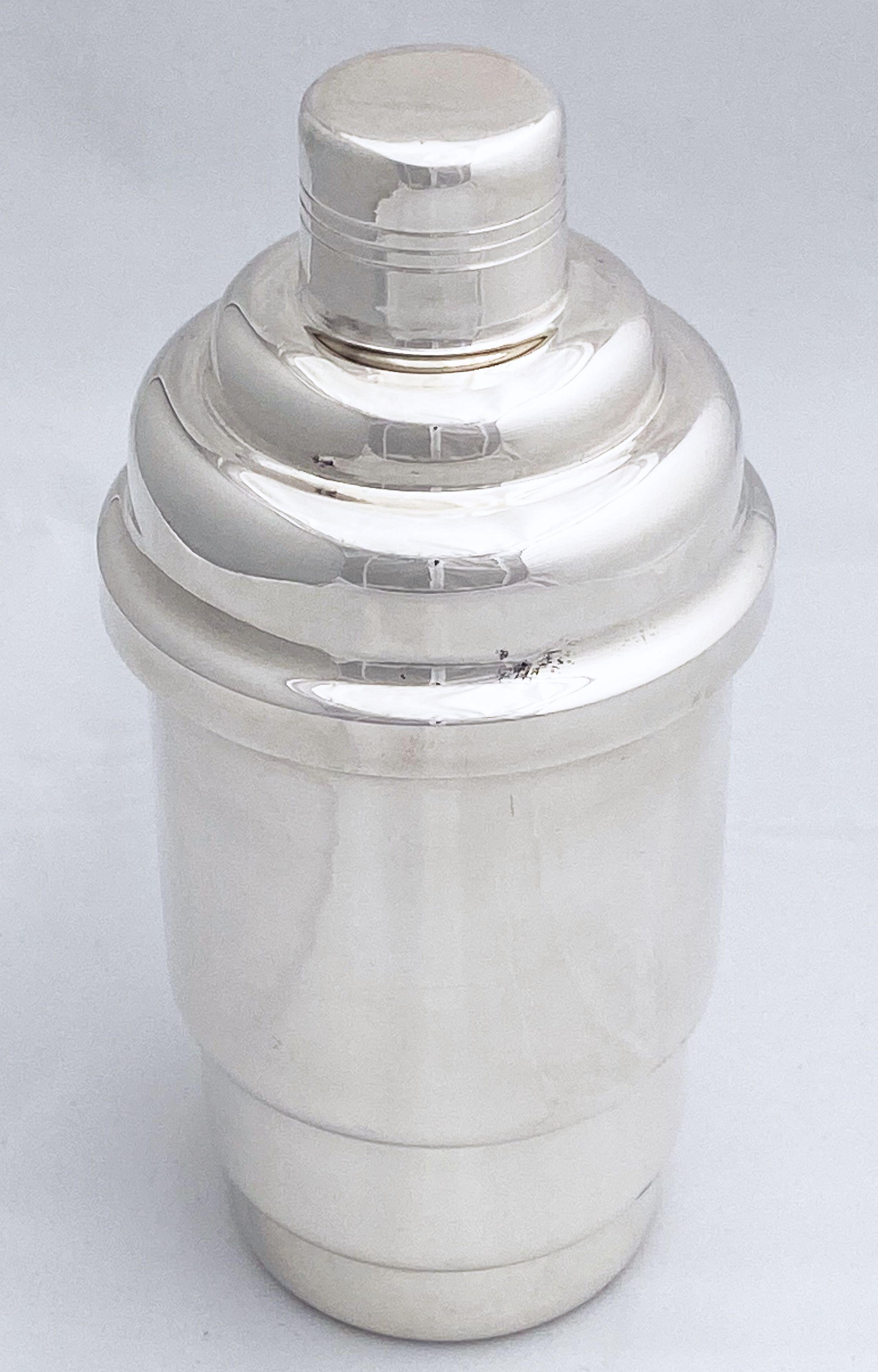 An authentic French cylindrical martini or cocktail shaker of fine plate silver, featuring Art Deco styling of graduating concentric circles, with removable cap and strainer.