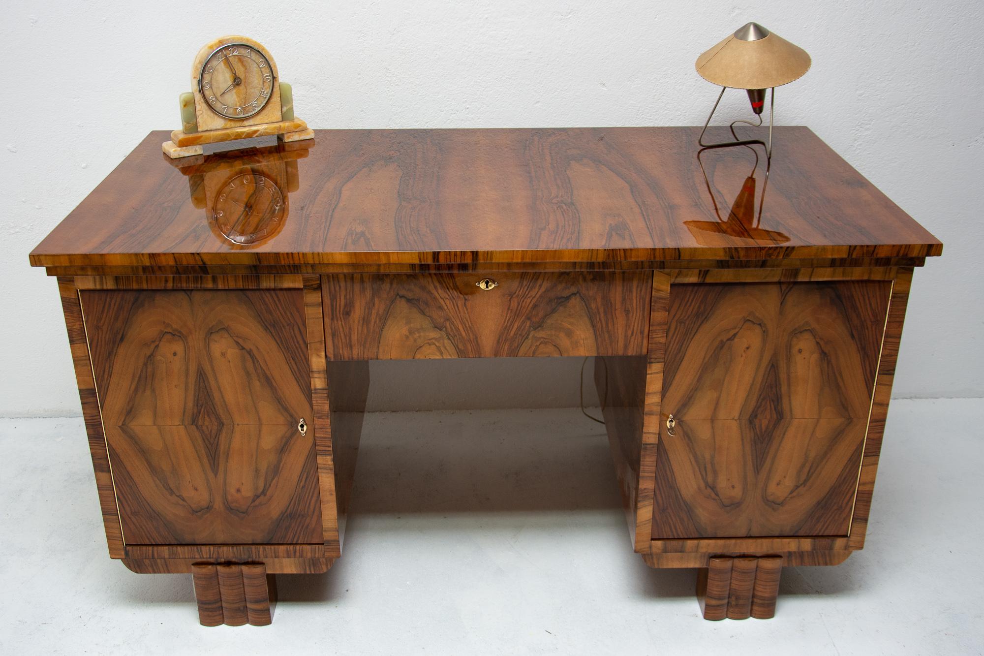 Massive Art Deco writing desk, made in the 1930s in Bohemia. It features a rectangular legs and walnut veneer inlaid. It includes five drawers and one shelf. The desk is in excellent condition due to complete professional renovation.