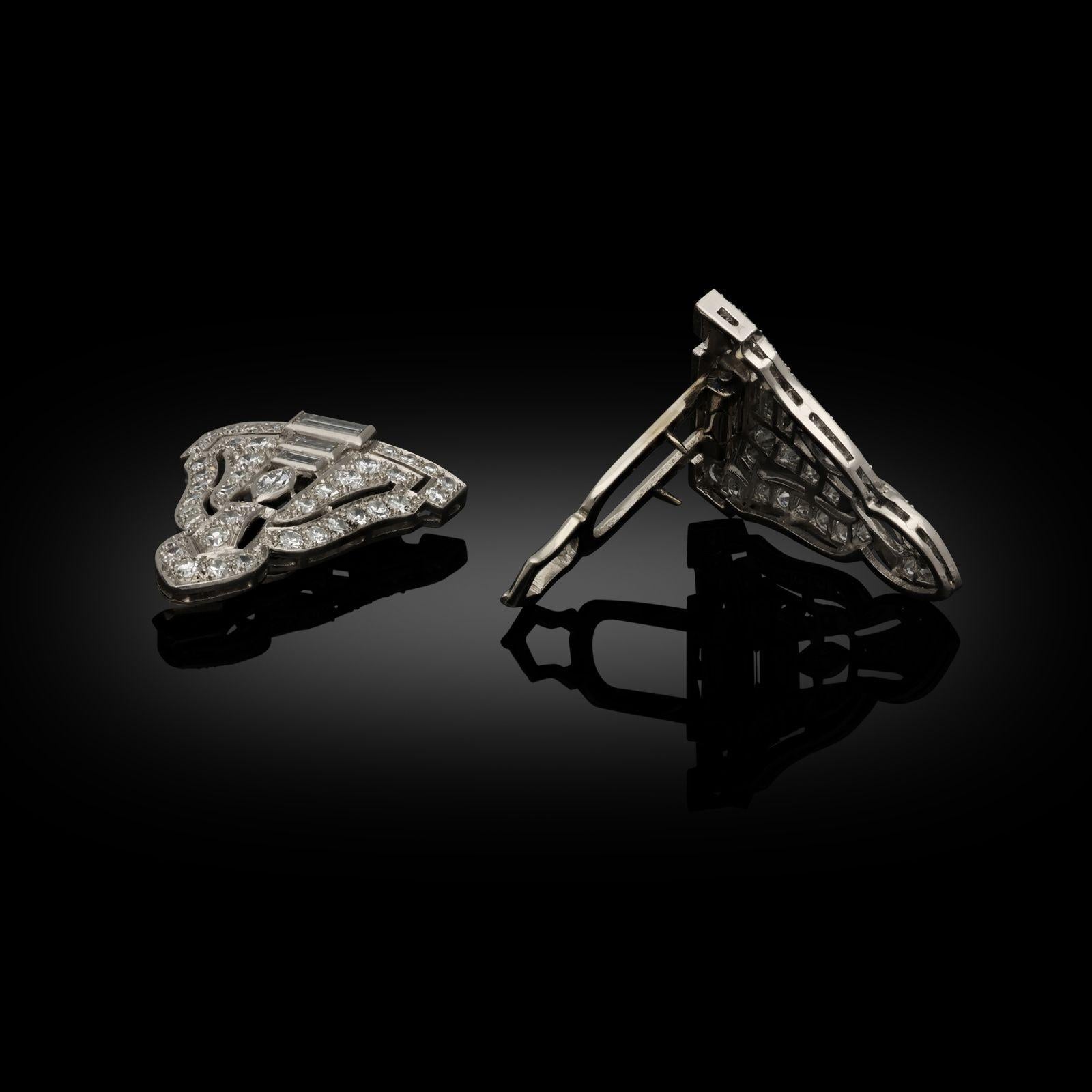 A beautiful pair of matching Art Deco diamond and platinum clips c.1925, each of triangular form and openwork design set with a mix of different diamond cuts including round, baguette and marquise cut all in rubover or grain settings, the reverse
