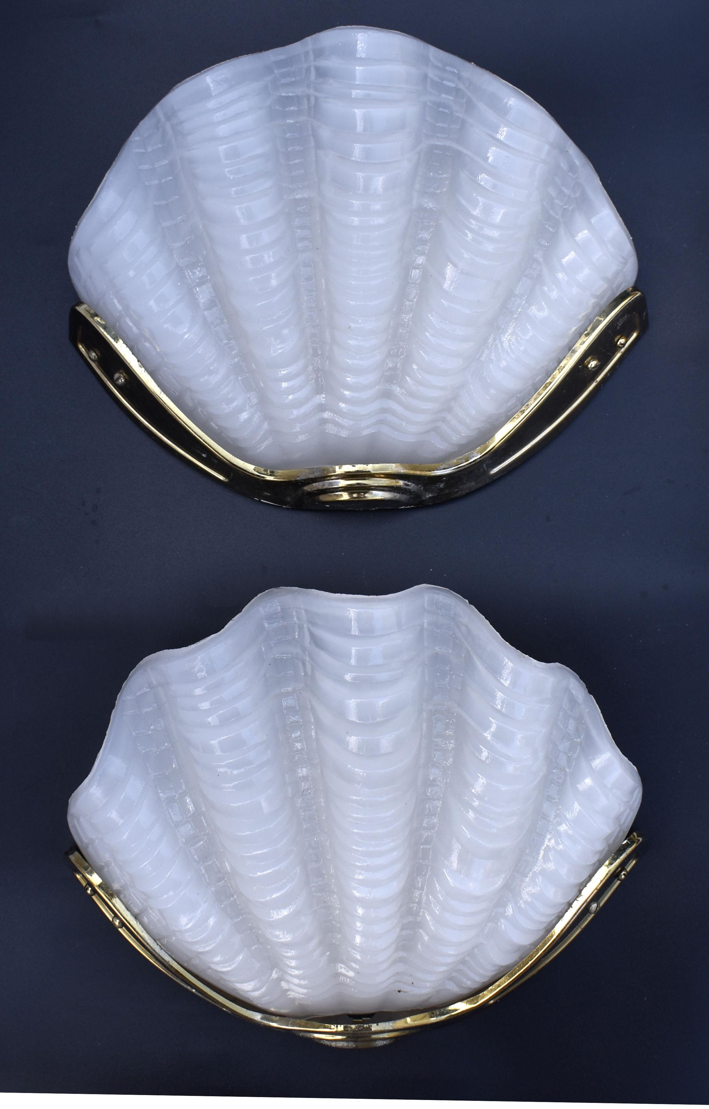 A beautiful matching pair of 1930's Art Deco wall lights of shell shape. The gilt frames are in very good original condition which when fitted to the wall hold the beautiful milk white opaque glass shades firmly in place. Very stylish and will work