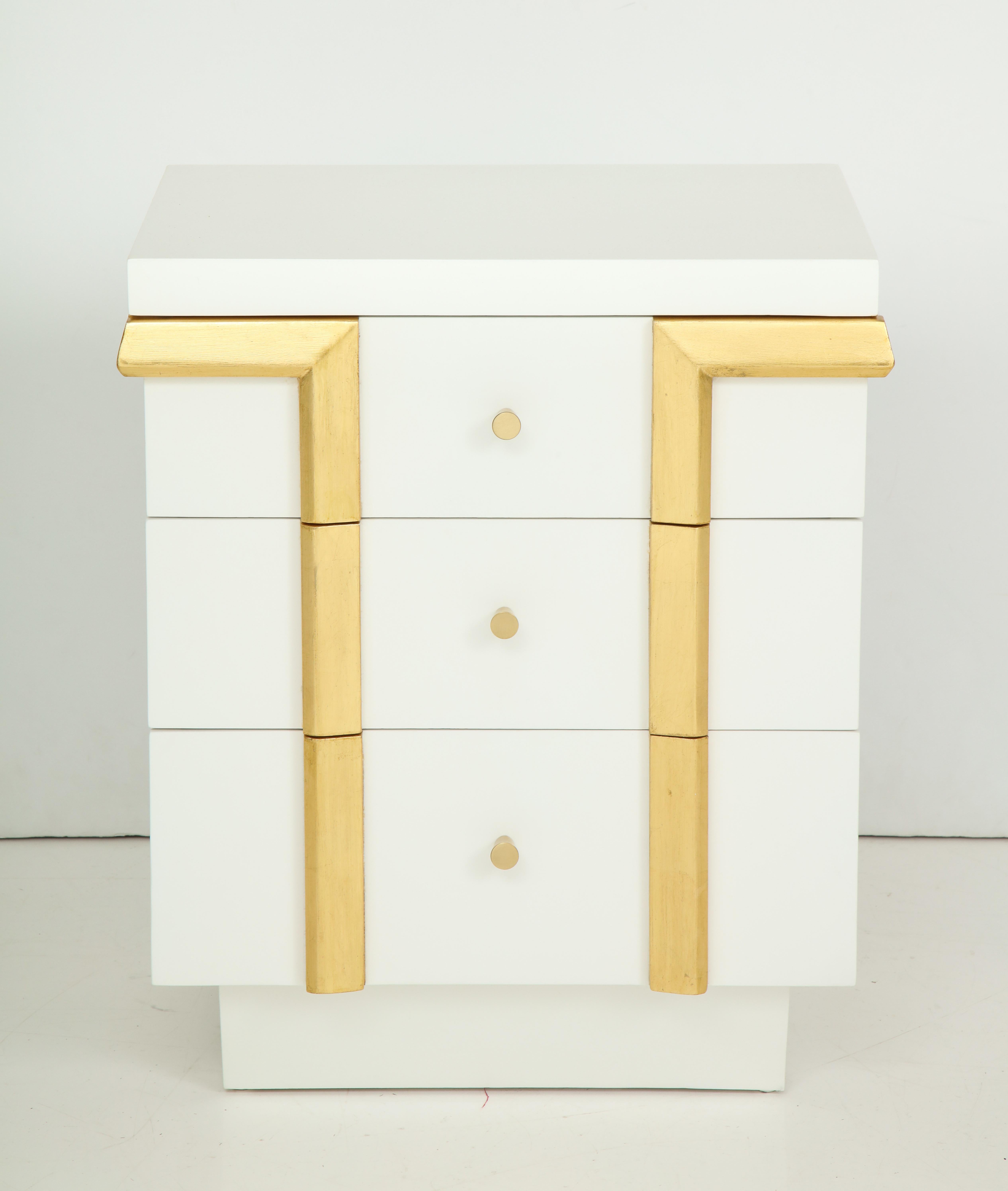 Pair of Art Deco, Hollywood Regency nightstands in a custom matte white lacquer finish with contrasting 22-karat gold leaf trim and satin brass conical pulls.