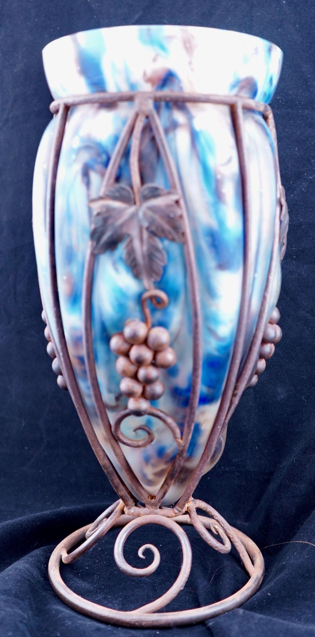 Vaso in vetro artistico soffiato Le Verre Francais con struttura in ferro. Il vaso è alto 14 pollici ed è debolmente firmato in oro, che si è cancellato. Il vetro è completamente intatto. Il telaio in ferro è leggermente arrugginito.
 