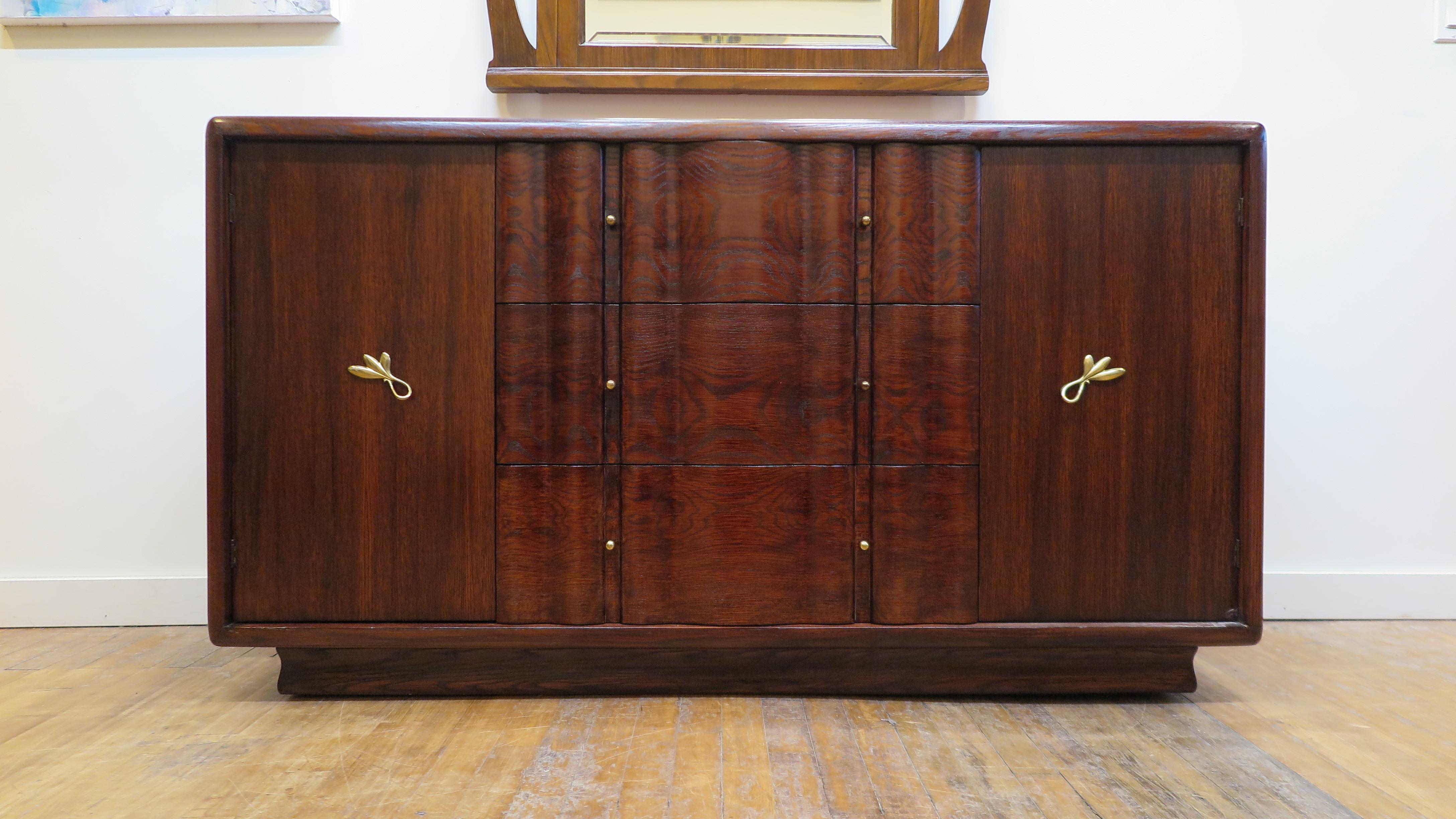 Art Deco Credenza sideboard. French inspired American Art Deco midcentury oak sideboard, 1940-1950. Waterfall edge case raised on plinth having three drawers, upper drawer with two flatware compartments, two cabinets for storage left and right.