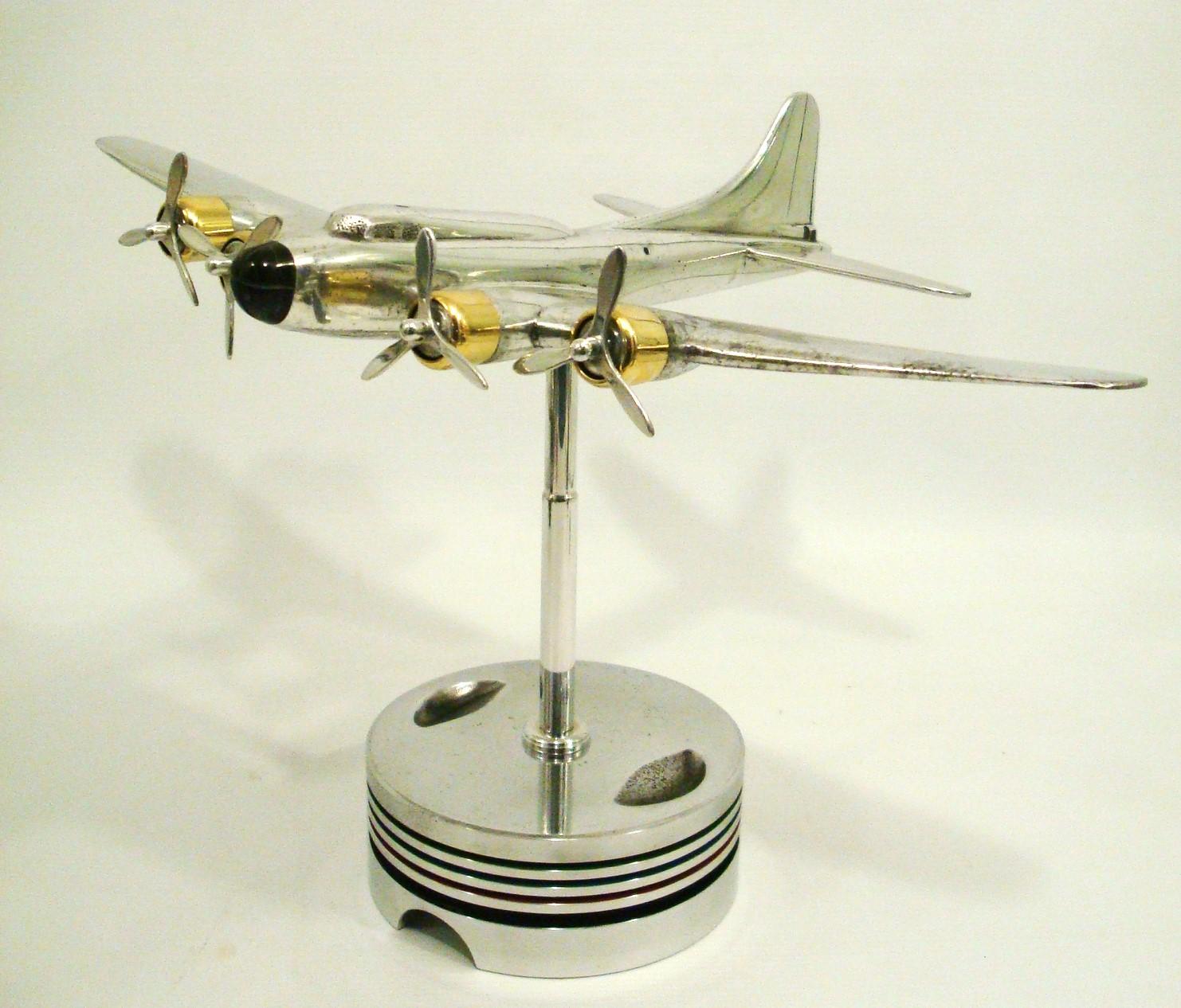Modèle d'avion de bureau Art déco du milieu du siècle monté sur un socle. L'avion est un quadrimoteur à hélice, chaque moteur étant équipé d'une hélice à pales multiples. Le modèle est métallique, avec une surface brillante et réfléchissante. Le