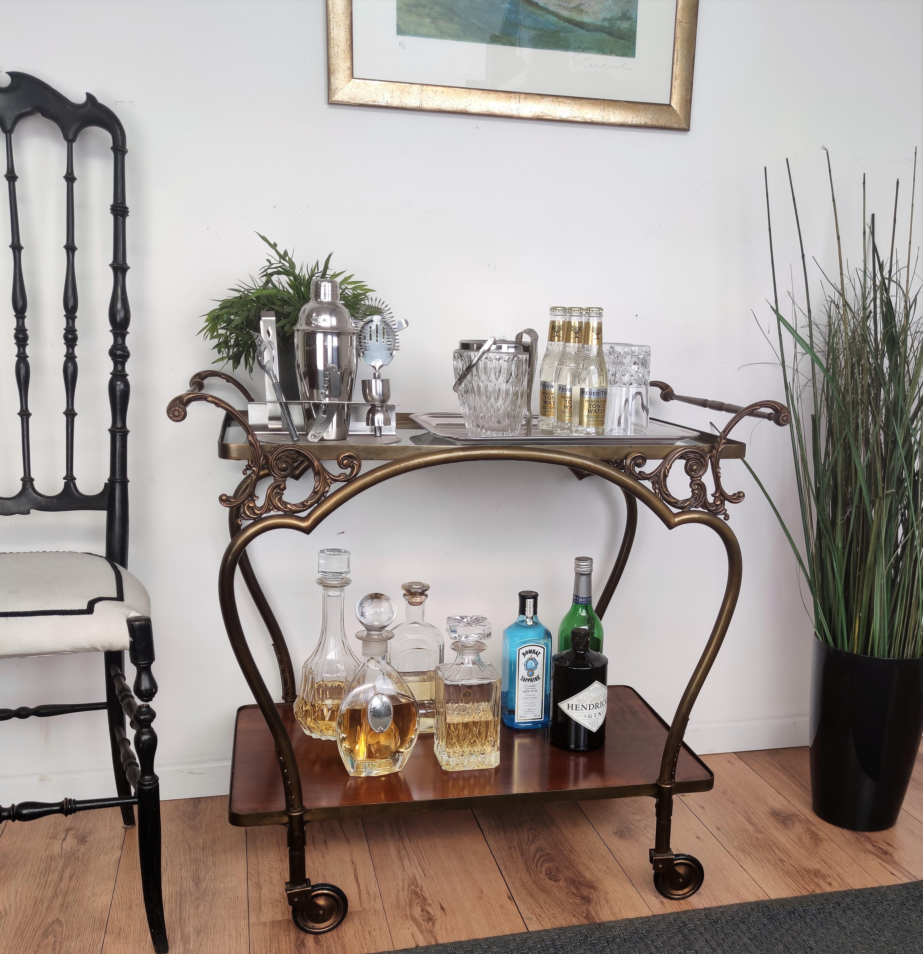 Bellissimo ed elegante carrello da bar vintage degli anni '50 in ottone a due livelli con piano in vetro. Ottime condizioni e cura dei dettagli come i decori delle maniglie e delle estremità delle ruote. Un grande pezzo che aggiunge perfettamente