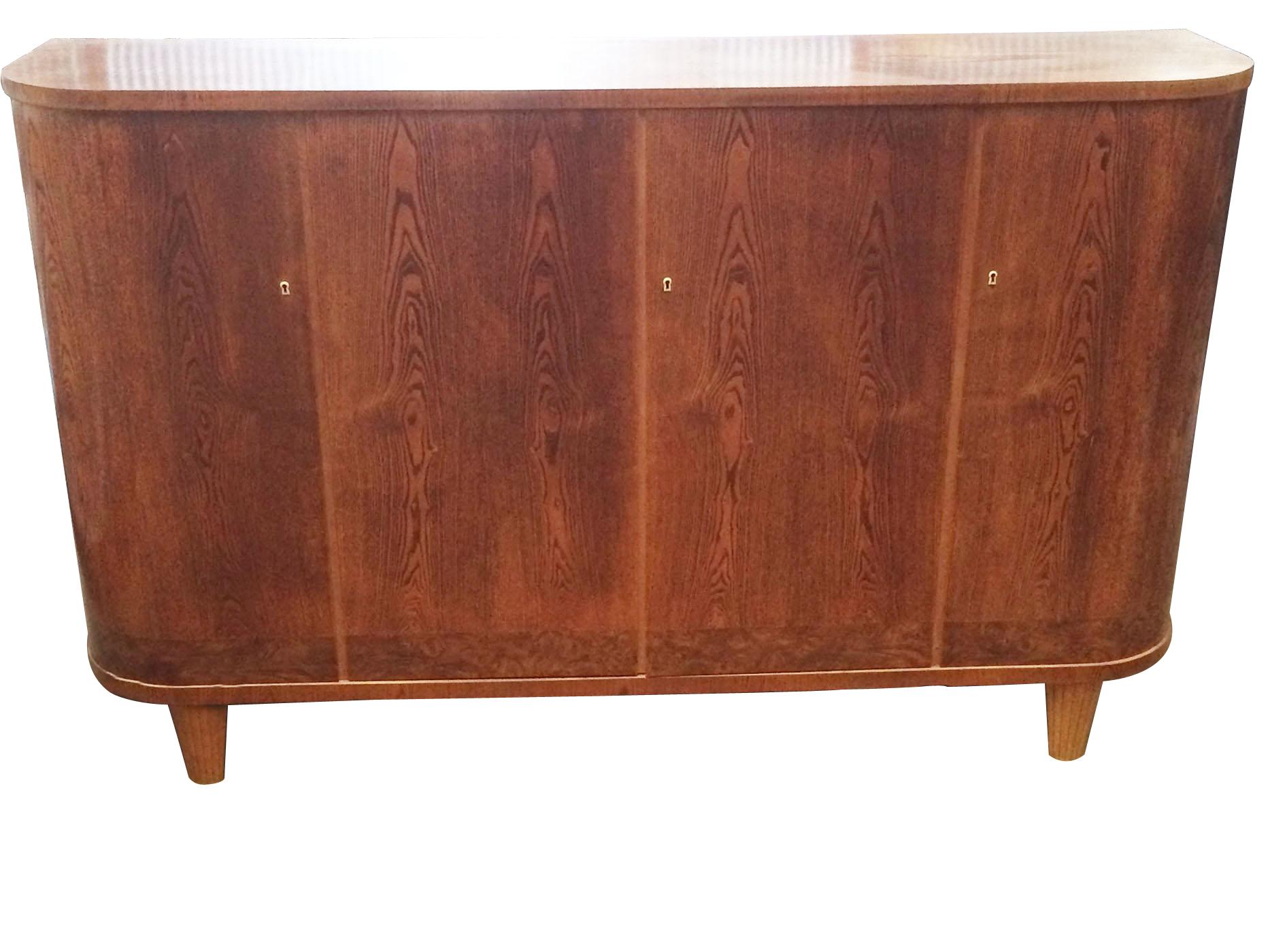 An exception late Art Deco or midcentury birch sideboard or cabinet. The sideboard has curved, ¼ circle ends and fluted. Tapered legs and white celluloid escutcheons for the 3 key holes. Interior has 2 interior shelves.
Dimensions: 45cm deep x