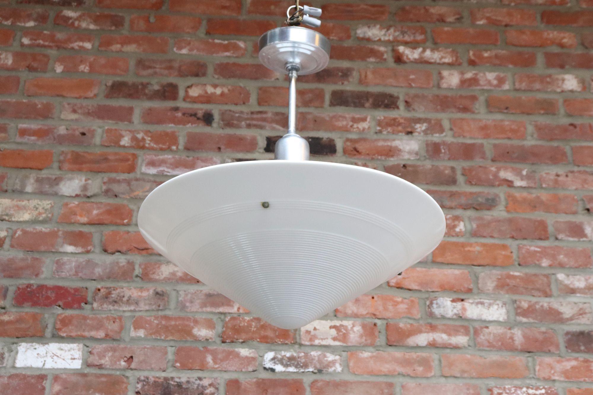 Pendente Art Déco a forma di cono con motivo a cerchi concentrici che conserva la goccia/copertina originale in cromo e alluminio (ca. 1930, USA).
Un pezzo elegante che diffonde un'attraente luce morbida attraverso il vetro crema-latte.
Condizioni