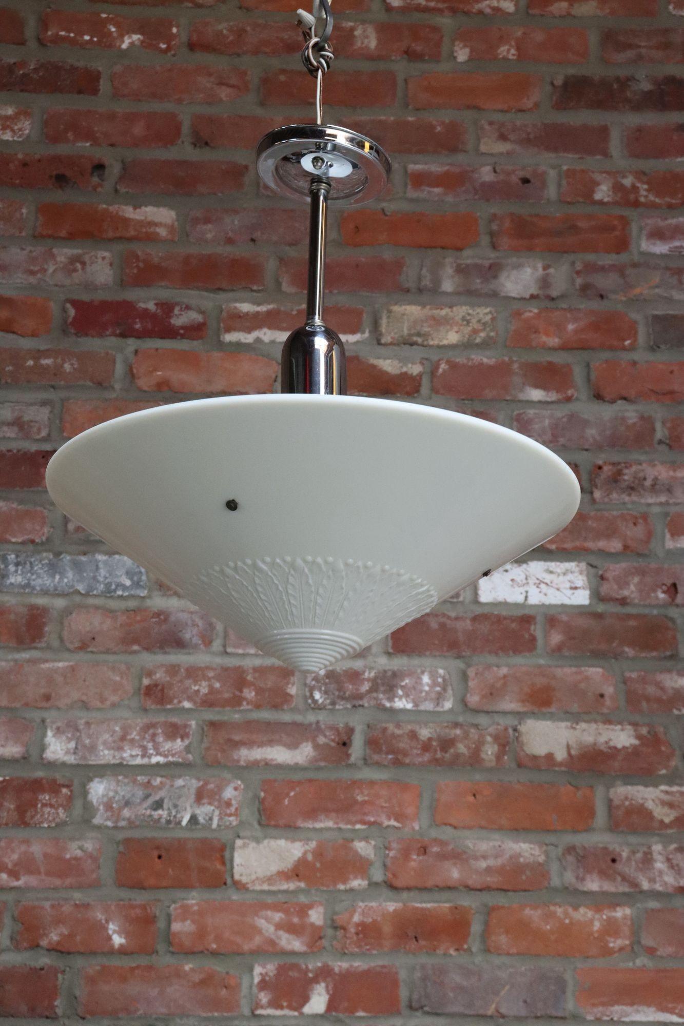 Pendente Art Deco a forma conica con motivo a foglie smerlate e cerchi concentrici con goccia e baldacchino in metallo (1930 circa, USA).
Un pezzo elegante che diffonde un'attraente luce morbida attraverso il vetro crema-latte.
Condizioni vintage