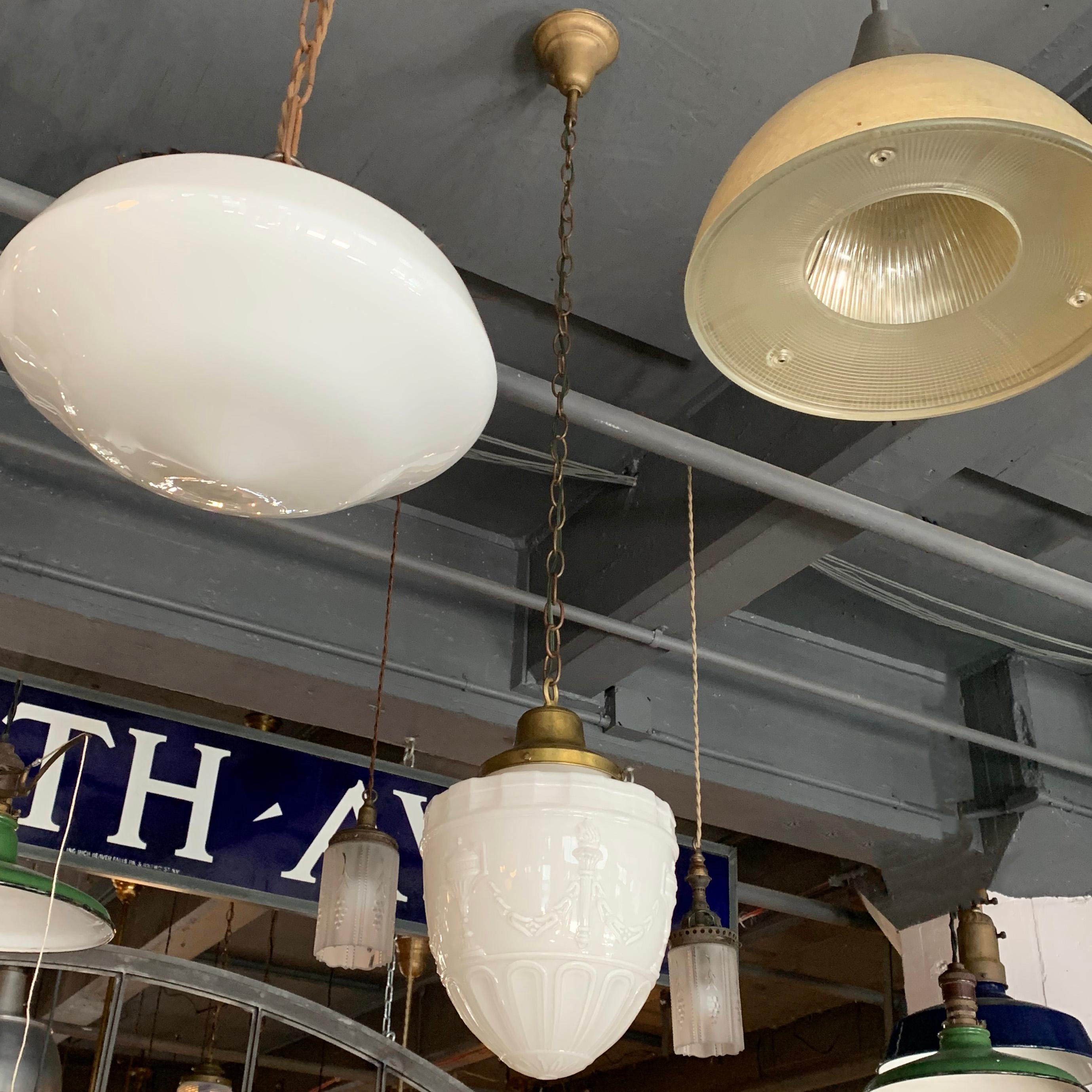 Early 20th century, Art Deco library pendant light features an ornate, oblong, milk glass shade with brass fitter, chain and canopy that hangs at an overall height of 58 inches.