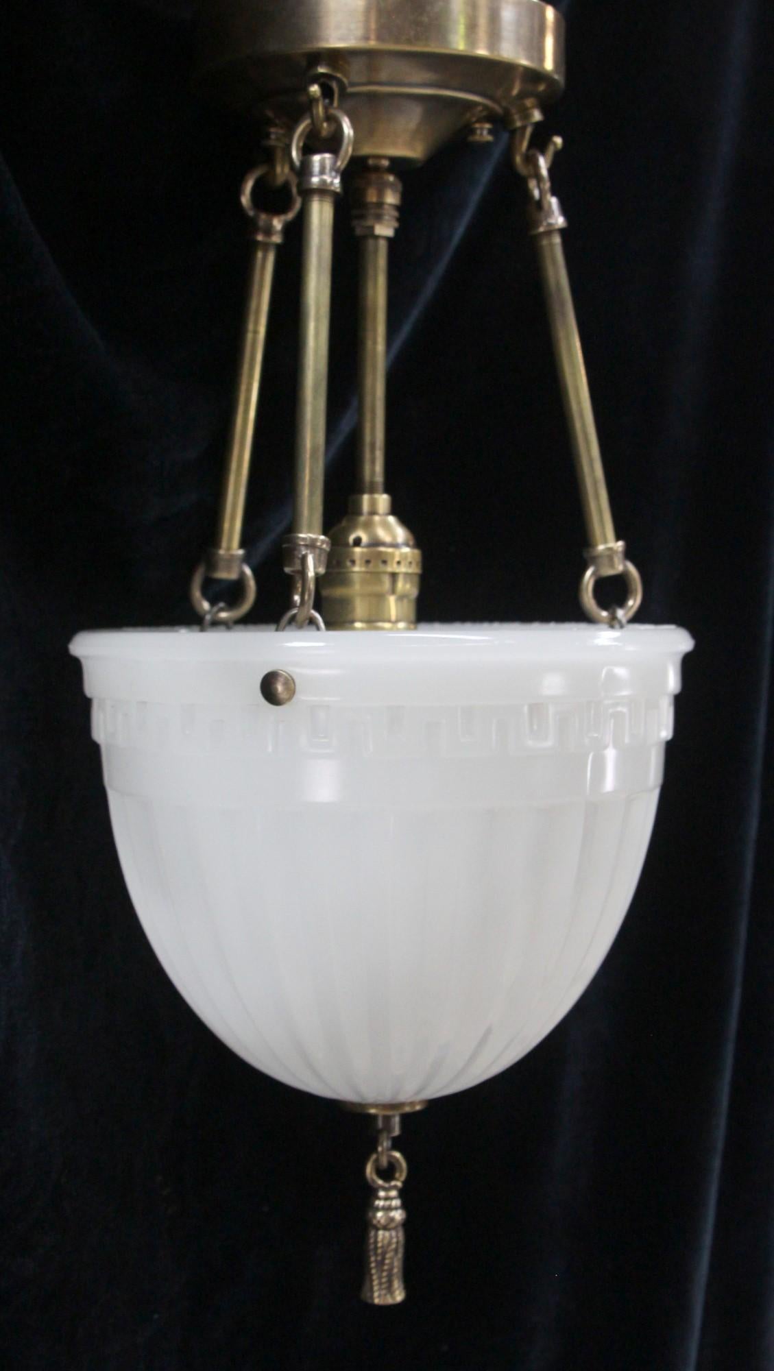 Original 1910s milk glass shade featuring Greek key detail reworked with new wired brass fitter to complete a hanging pendant light. It's brass rope tassel also gives it a nice additional accent. Cleaned ad rewired. Small quantity available at time