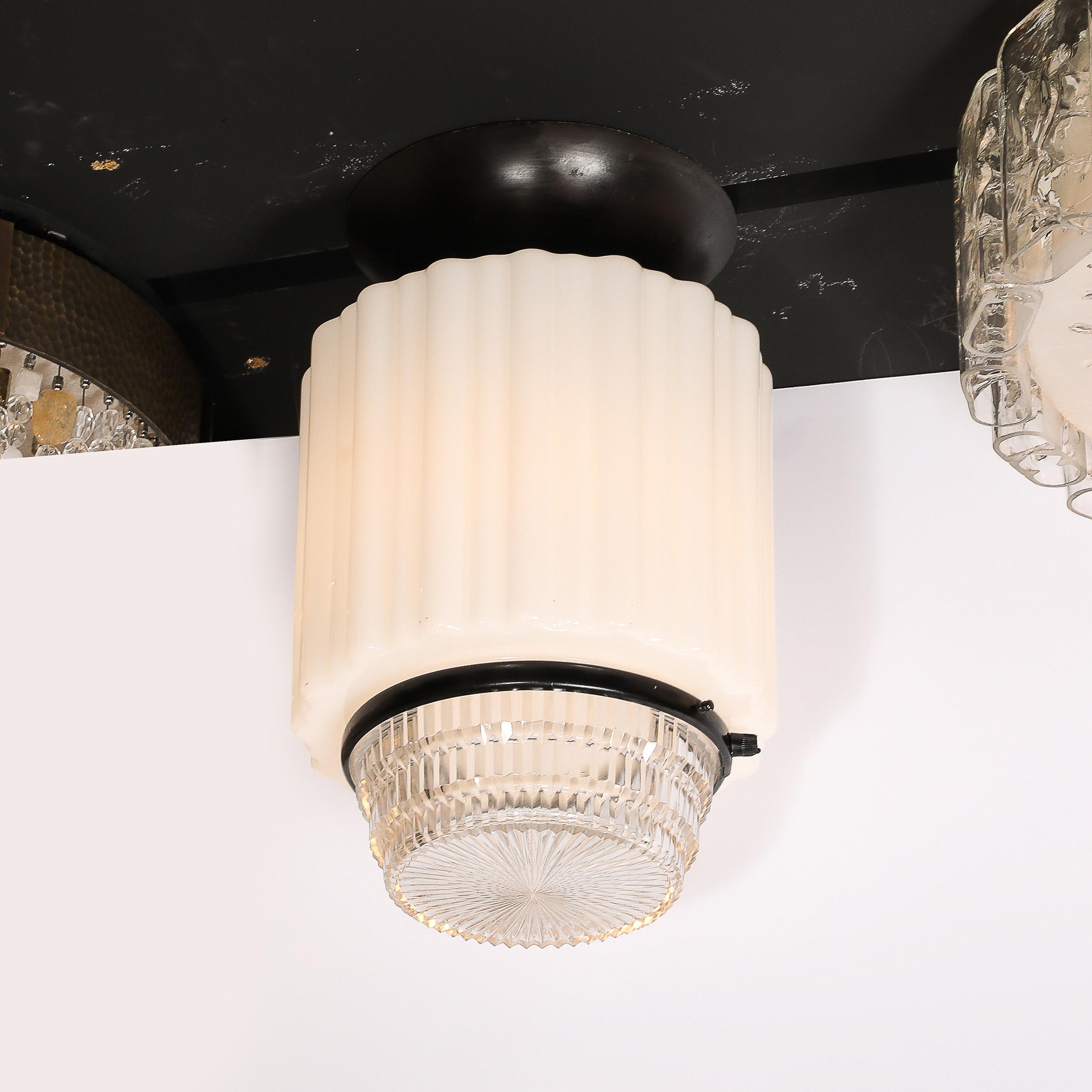 Questo lampadario a sospensione Art Deco in vetro lattimo e vetro pressato, ben composto e materialmente dinamico, con accessori in bronzo, proviene dagli Stati Uniti, circa dal 1930. Presenta un paralume primario in vetro Milk Glass con dettagli
