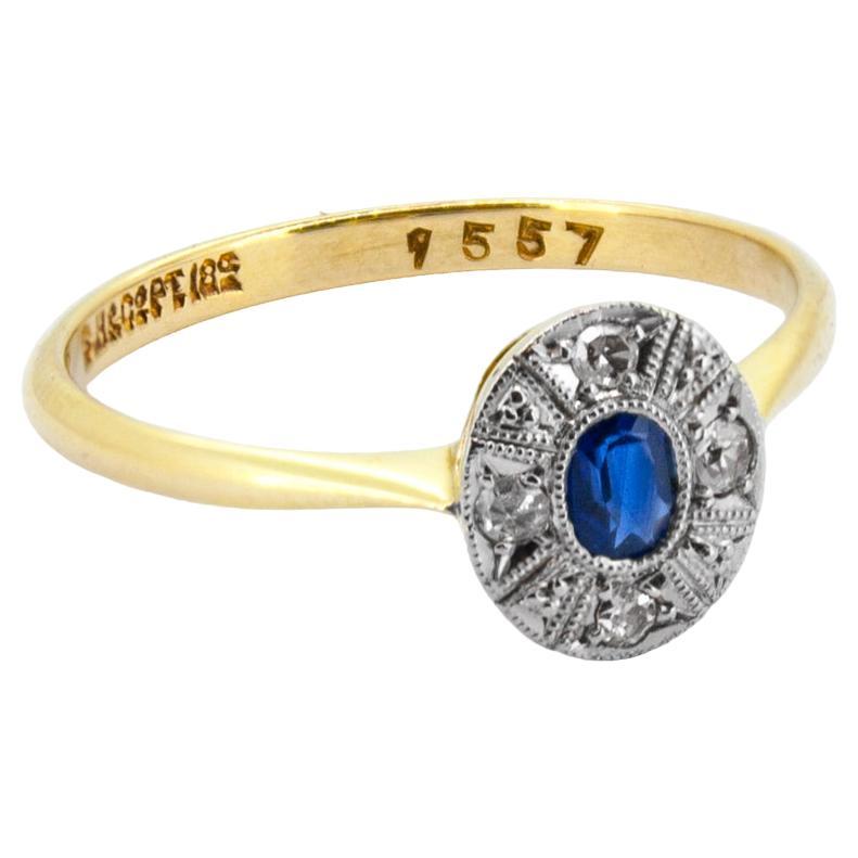 Dieser Art Deco Sapphire & Diamond Cluster Ring ist perfekt proportioniert. Der üppige blaue Sapphire wurde in der Art Deco Ära kreiert und ist von einer Reihe von Diamanten im Einzelschliff umgeben. Dezent und elegant zugleich, ist sie eine der