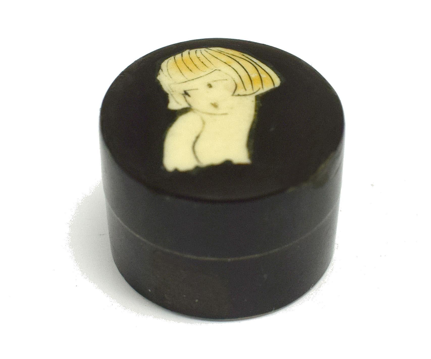 Miniature Art Deco 1930's powder box in bakelite with a hand painted 1920's girl with a bob haircut to the lid. There is still a residue of powder in the base. This piece is likely an item carried in an evening bag and allows for a touch up of make