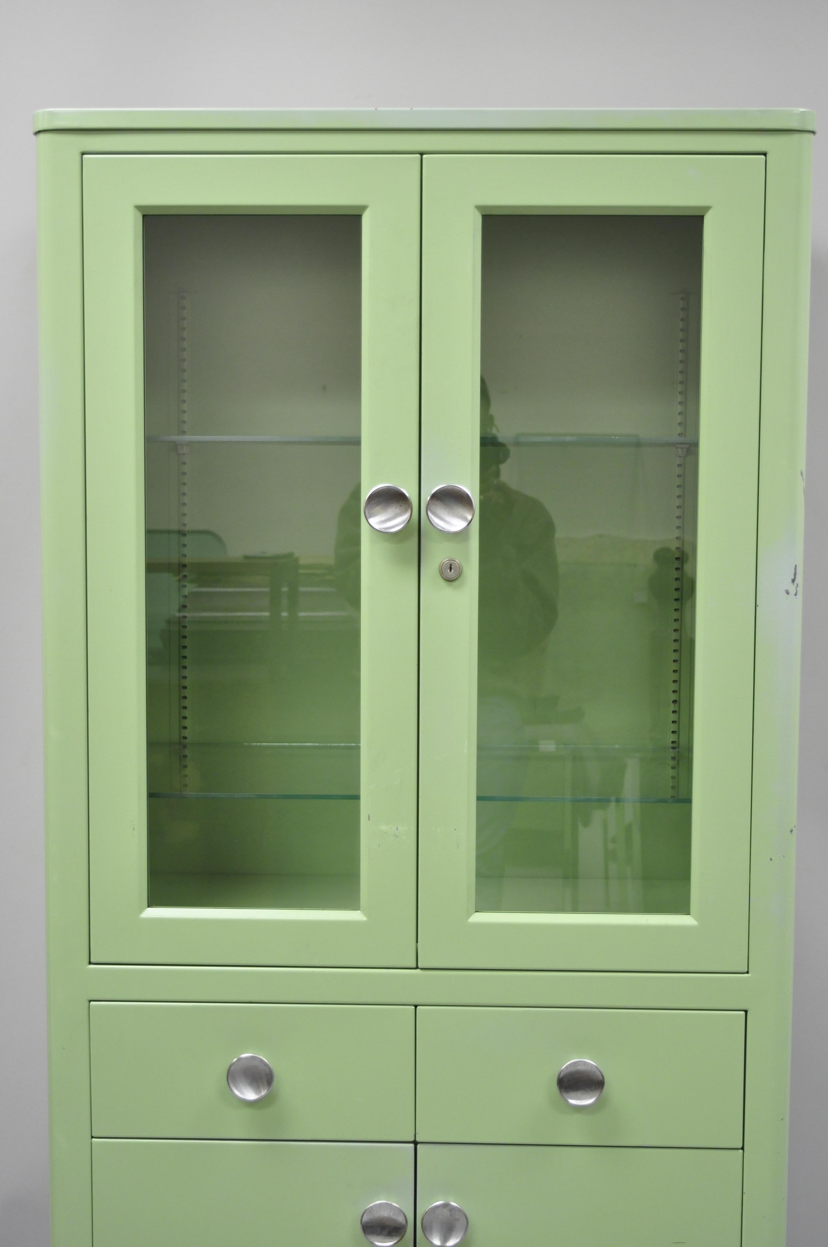 Art Deco mint green steel dental cabinet display by United Metal. Item features steel metal frame, original mint green, (1) extra glass shelf, 4 swing doors, no key but unlocked, 2 drawers, great style and form. Measurements: 67