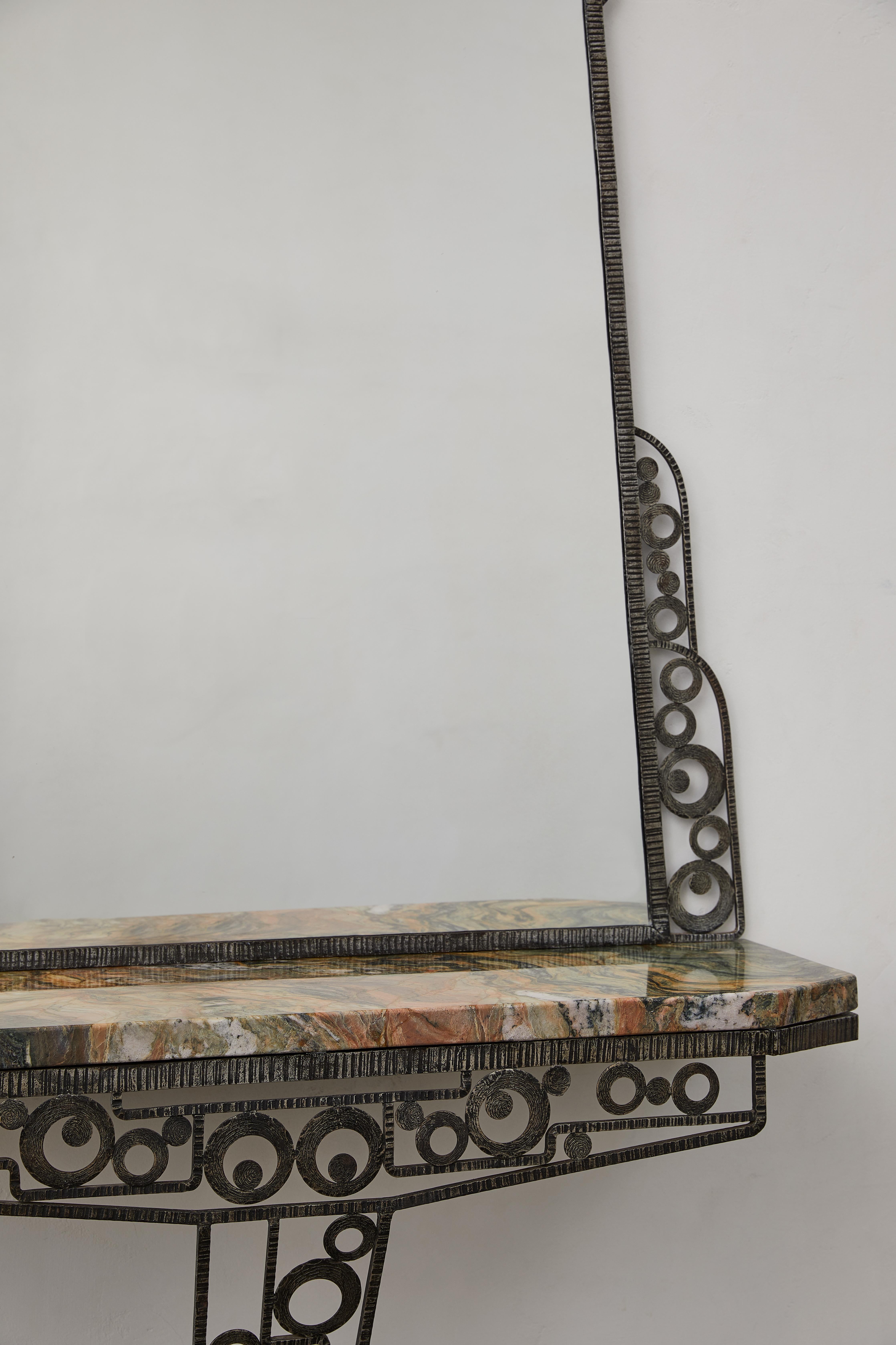 This Art Deco mirrored console by Edgar Brandt is a striking fusion of form and function. Handmade in France, c. 1925, it features hammered wrought iron with intricate geometric detailing, embodying the elegance of early 20th-century metalwork. A