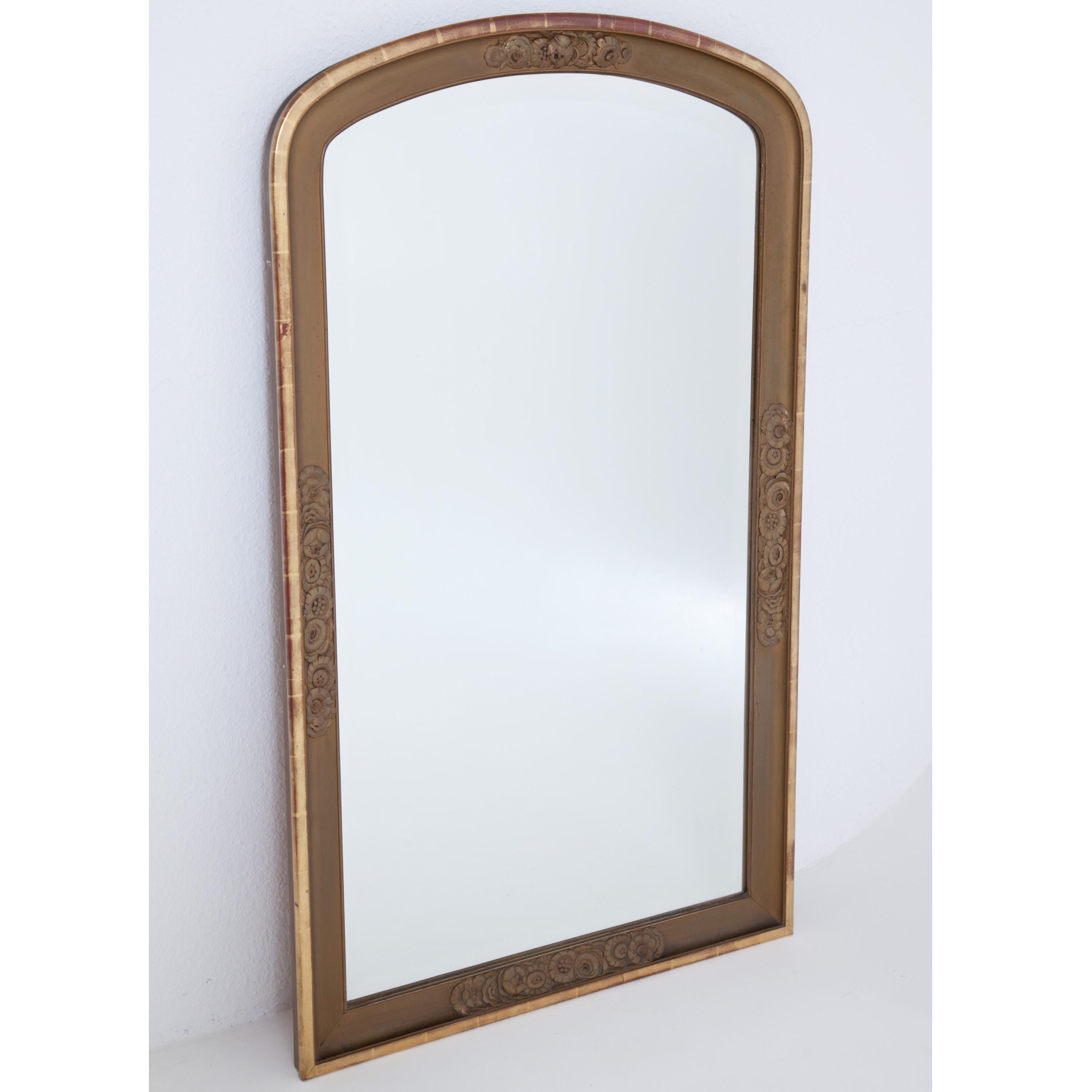 Large wall mirror in Art Deco style. The rounded frame with relief floral decoration. Wood, partly gold patinated.