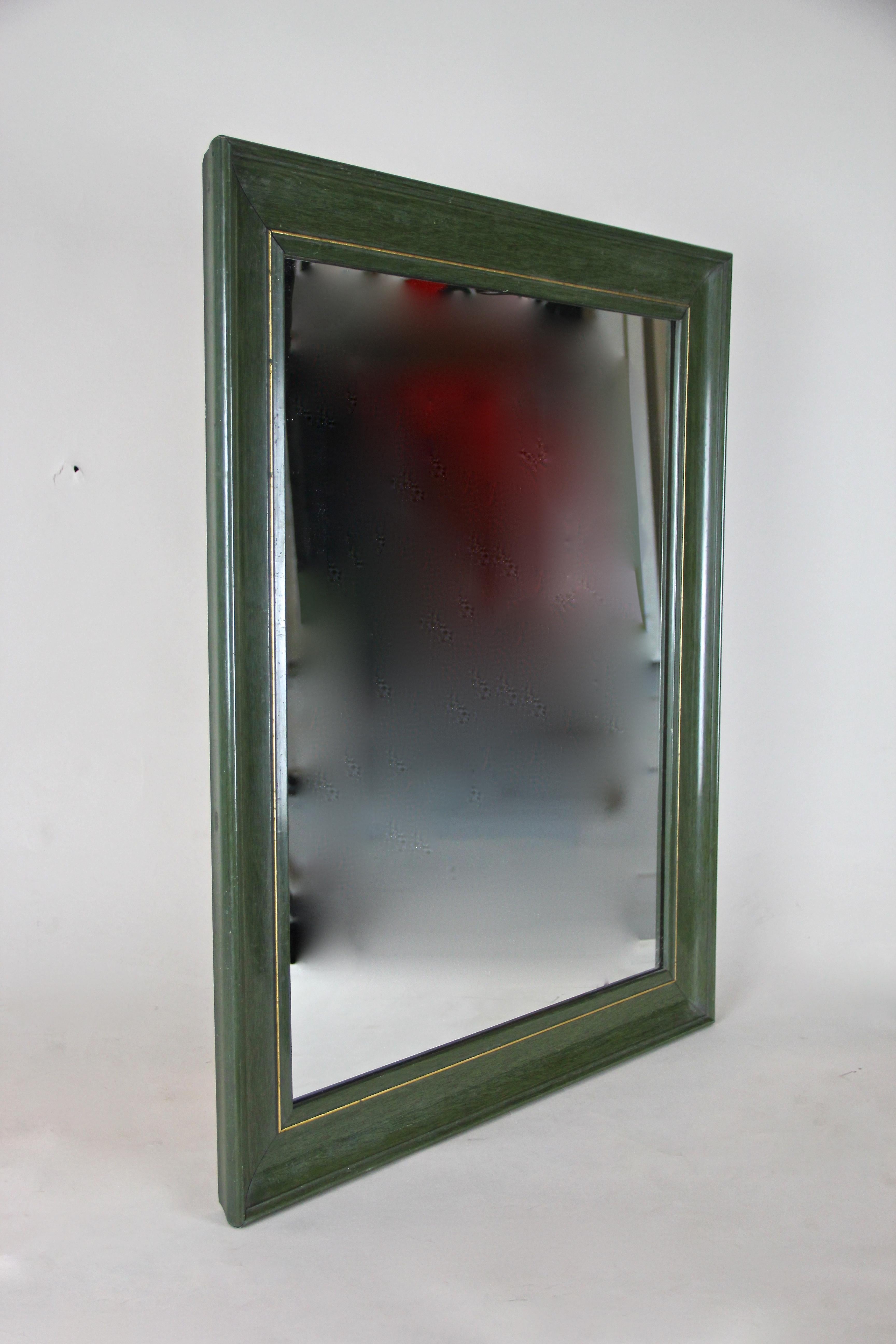 Timeless Art Deco mirror from Austria, circa 1930. The lacquered frame shows a beautiful olive green surface. This straight designed wall mirror was additionally decorated by an inlayed brass strip. Unfortunately the original mirror glass was