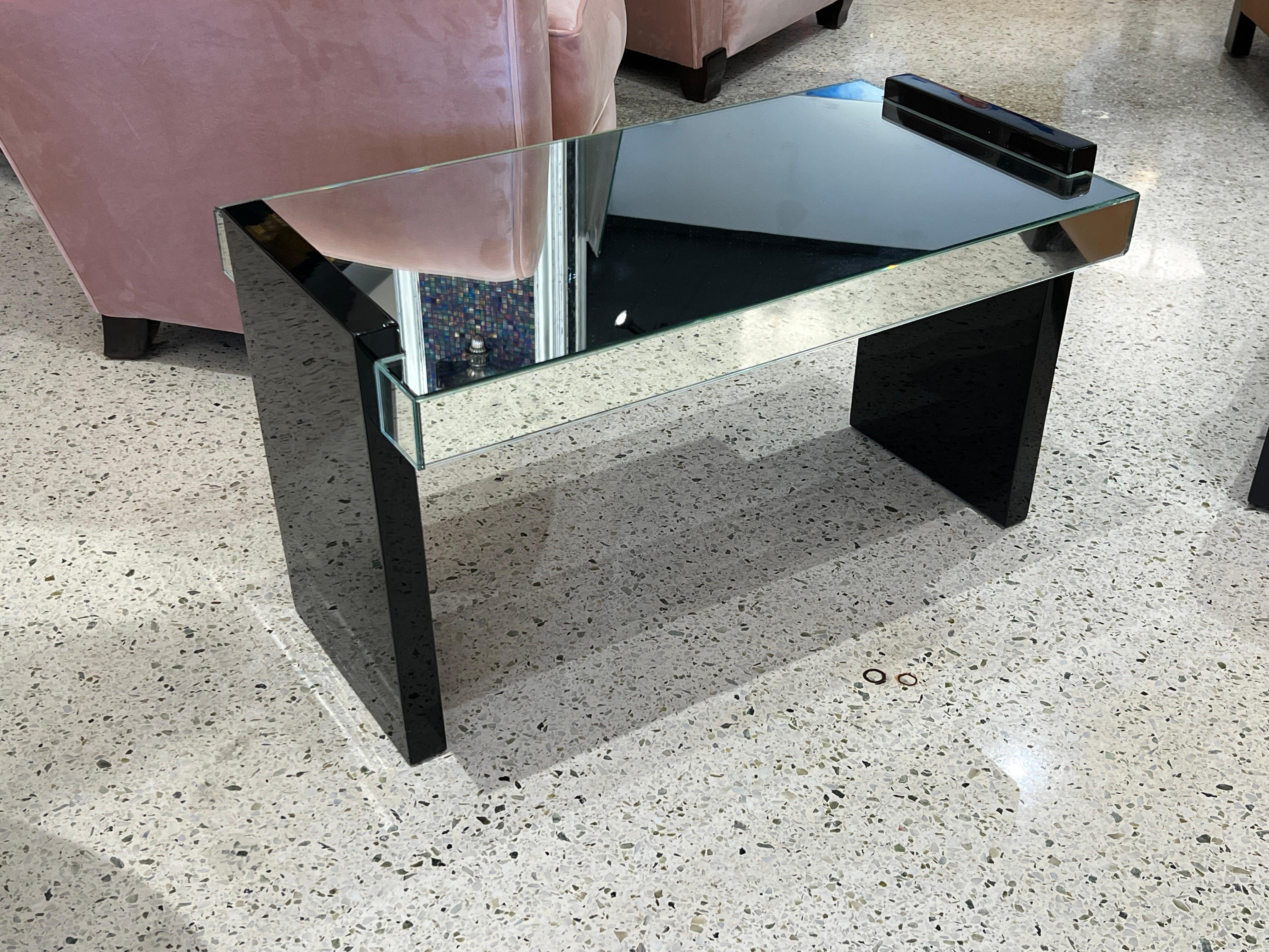 Art Deco rectangular side table in black Lacquer with mirror top by Jacques Adnet.

Jacques Adnet was an iconic Art Deco French designer. His designs featured clean lines, simple shapes and contrasting materials, giving them a unique and timeless