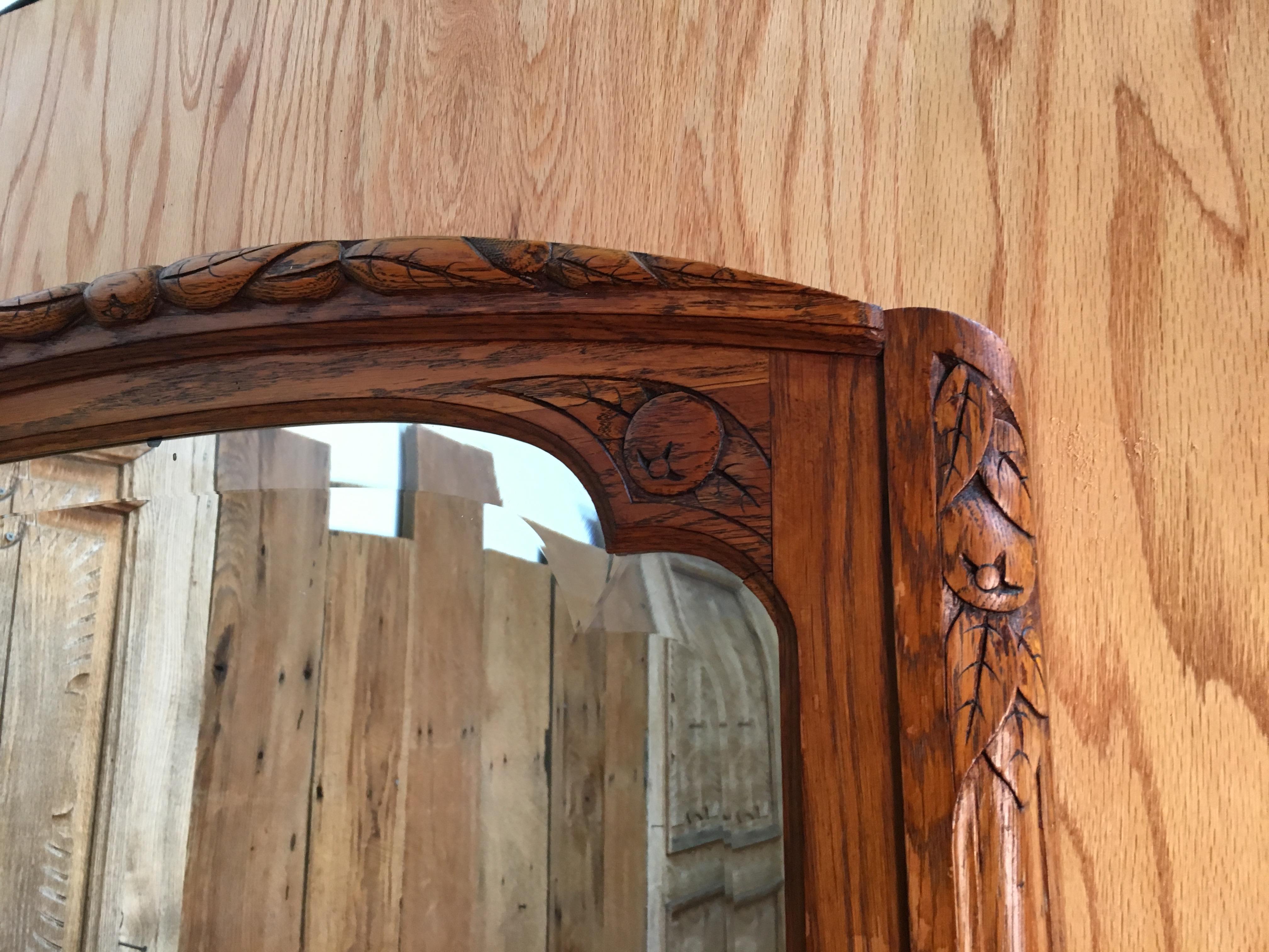 Carved foliage on this Art Deco frame with large beveled mirror.