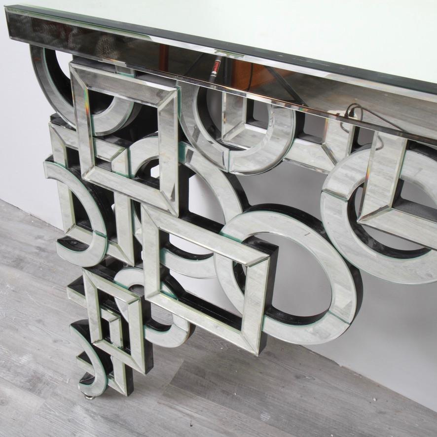 Art Deco -inspired mirrored console table that affixes to the wall with two screws hidden underneath. Mirrored pieces are glued to a matt black composite backing of the same shape. Well made and substantial. Two metal protective caps at base of