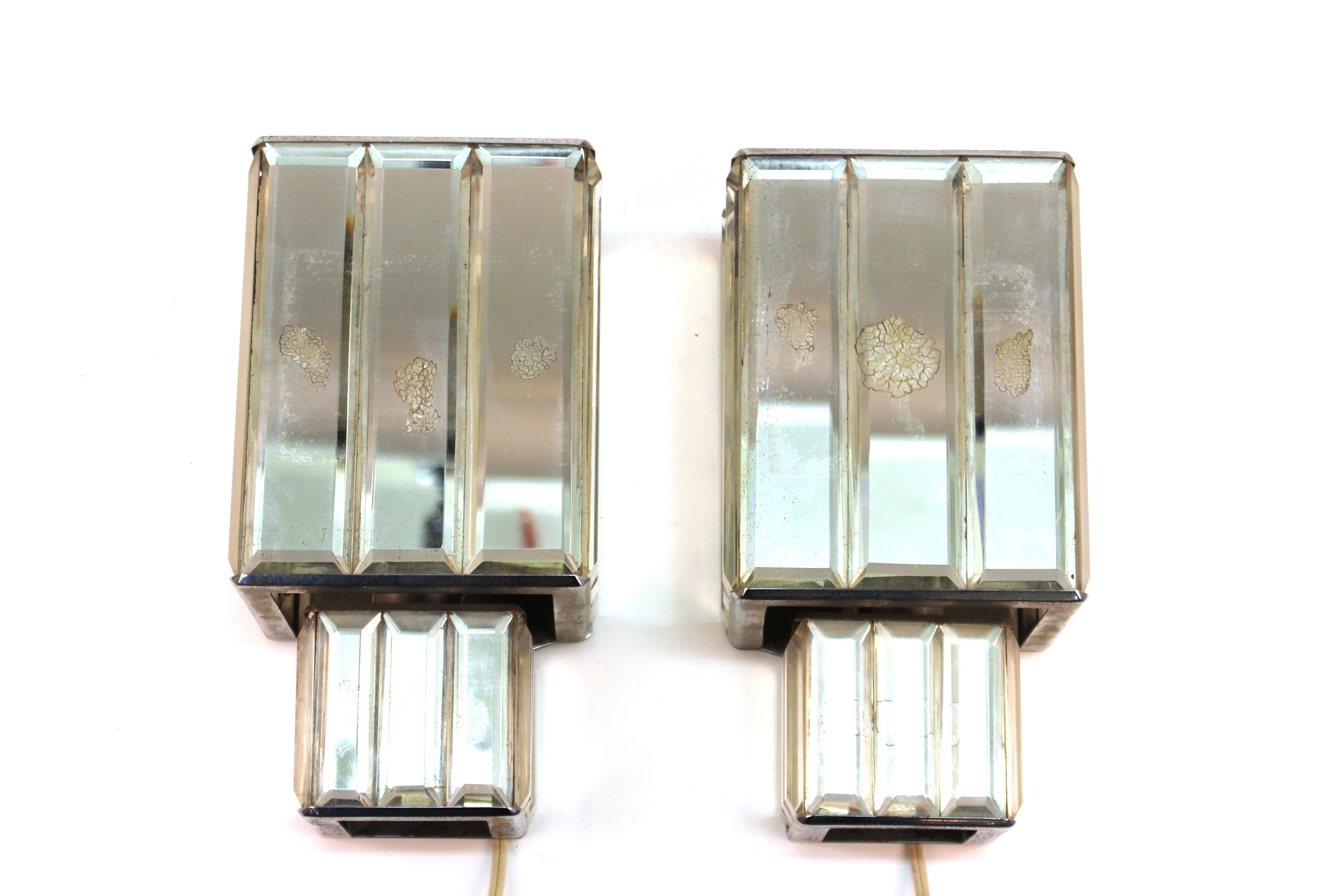 Art Deco period pair of wall sconces with metal structure and applied beveled mirrors and glass elements. The pair was likely made in Europe during the 1930s and is in great vintage condition with age-appropriate wear.
