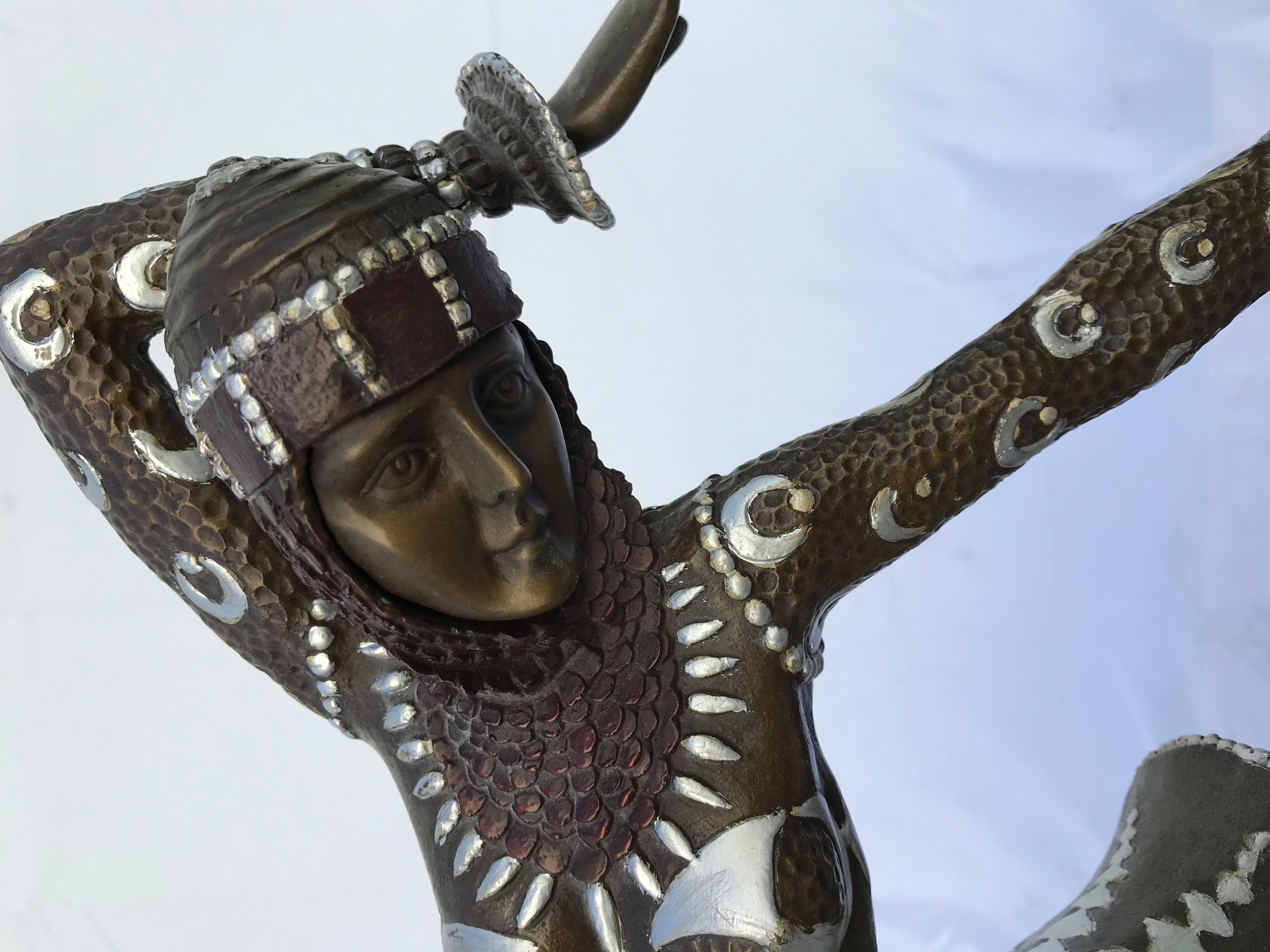 A deco dancer dressed in a detailed dress in a pose on one knee. Fine detailed quality bronze casting  with Cold painted details on her costume. The title listed is ( Karmorna ) by the well known artist D H Chiparus . Mounted on an elaborate