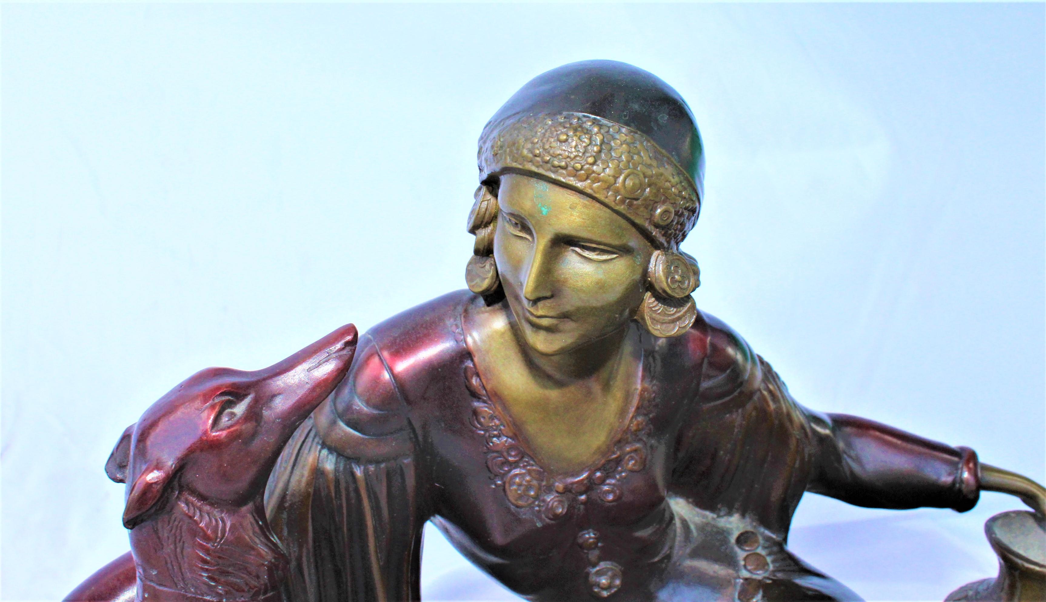 An Art Deco Sculpture of a lady in full dress sitting with her dog. Fine details and with multi-patina finishes. Seated on a deluxe fabricated large marble base at 22 1/2