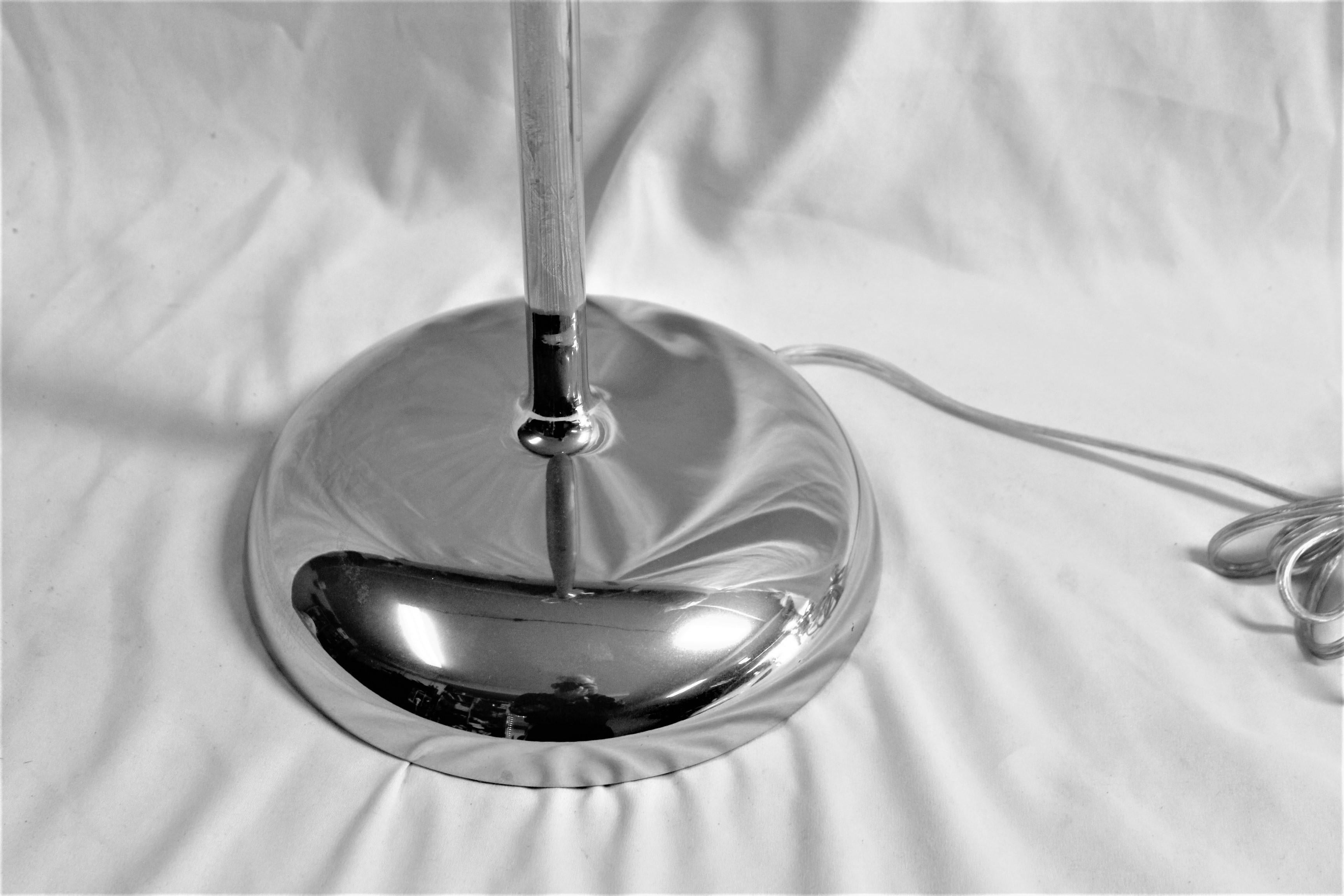 This modern lamp has a round spun smooth shaped base joined with a slender riser up to the socket mount . All put together and hi-polished metal .  Then Hi-polished Nickel plating applier .  It has a dimmable socket and wired with Silver cord.