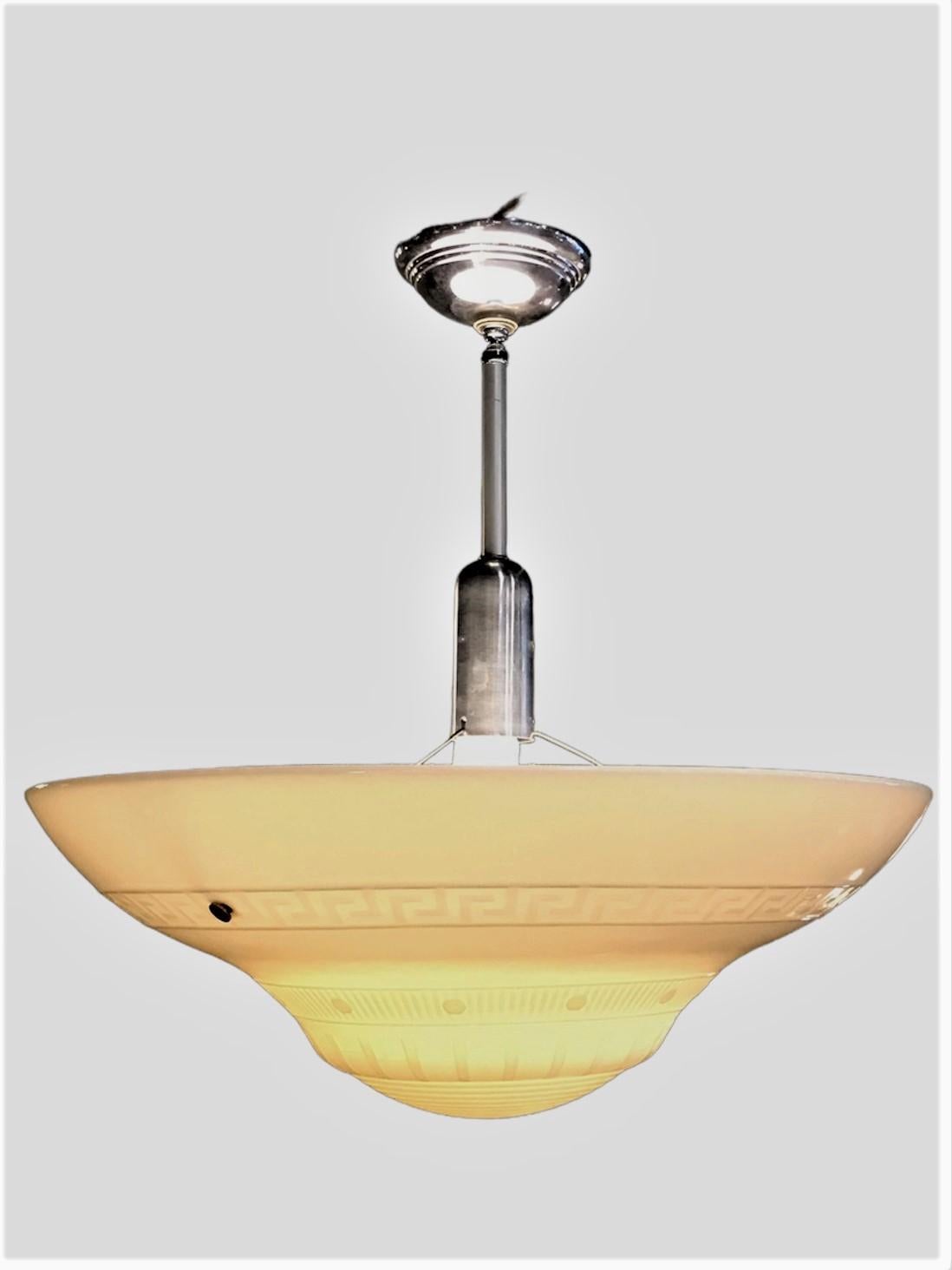 Sleek period Streamline Moderne Light featuring a wide conical thick milk glass bowl with concentric ribs on the bottom follow by bands of parallel lines and a wide Greek Key motif band (Meander). The glass shade suspended under a chromed bullet