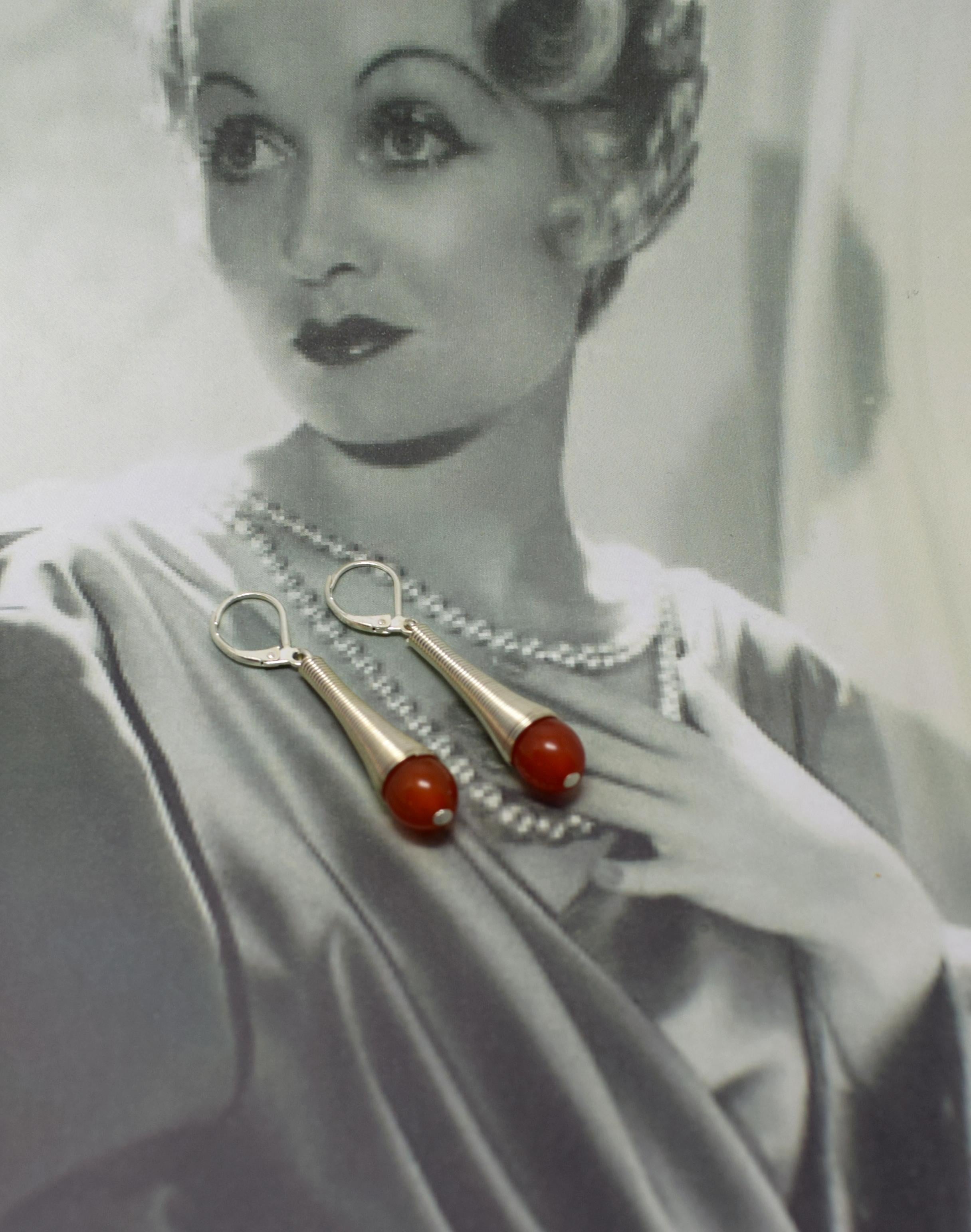 Boucles d'oreilles modernistes Art déco des années 1930, fabuleusement élégantes. La bakélite phénolique est de couleur rouge tomate. Le métal chromé est brillant et net, sans ternissement ni piqûre. Belle longueur au porter et idéal pour la journée