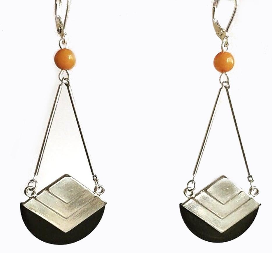 Beautiful piece of jewellery dating to the 1930's are these modernist pair of drop earrings. Features stepped geometric chevron shapes in mirror chrome with jet Black & Orange phenolic Bakelite accents. New Silver plated lever backed wires have been