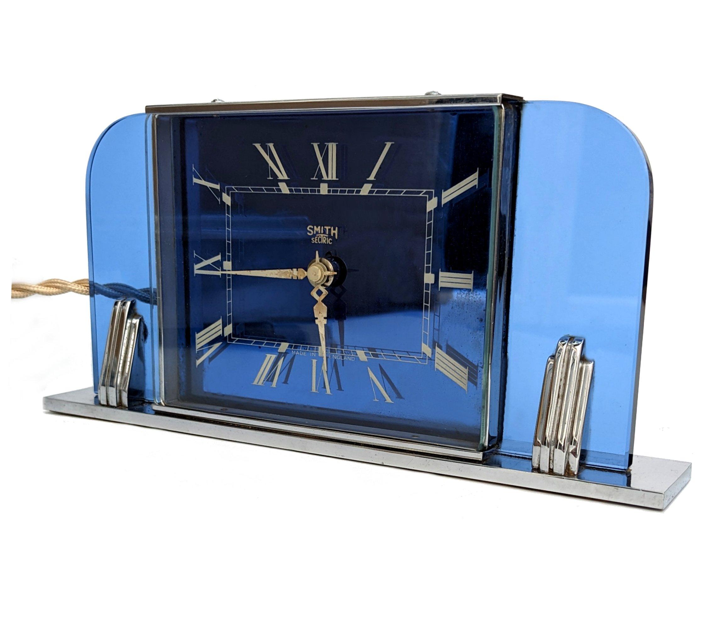 Very attractive and totally authentic 1930s Art Deco Smith's mantel clock dating from 1937 or soon thereafter. This clock has a wonderful blue glass case with a very heavy chrome base and chrome uprights. This clock is electric and working with good