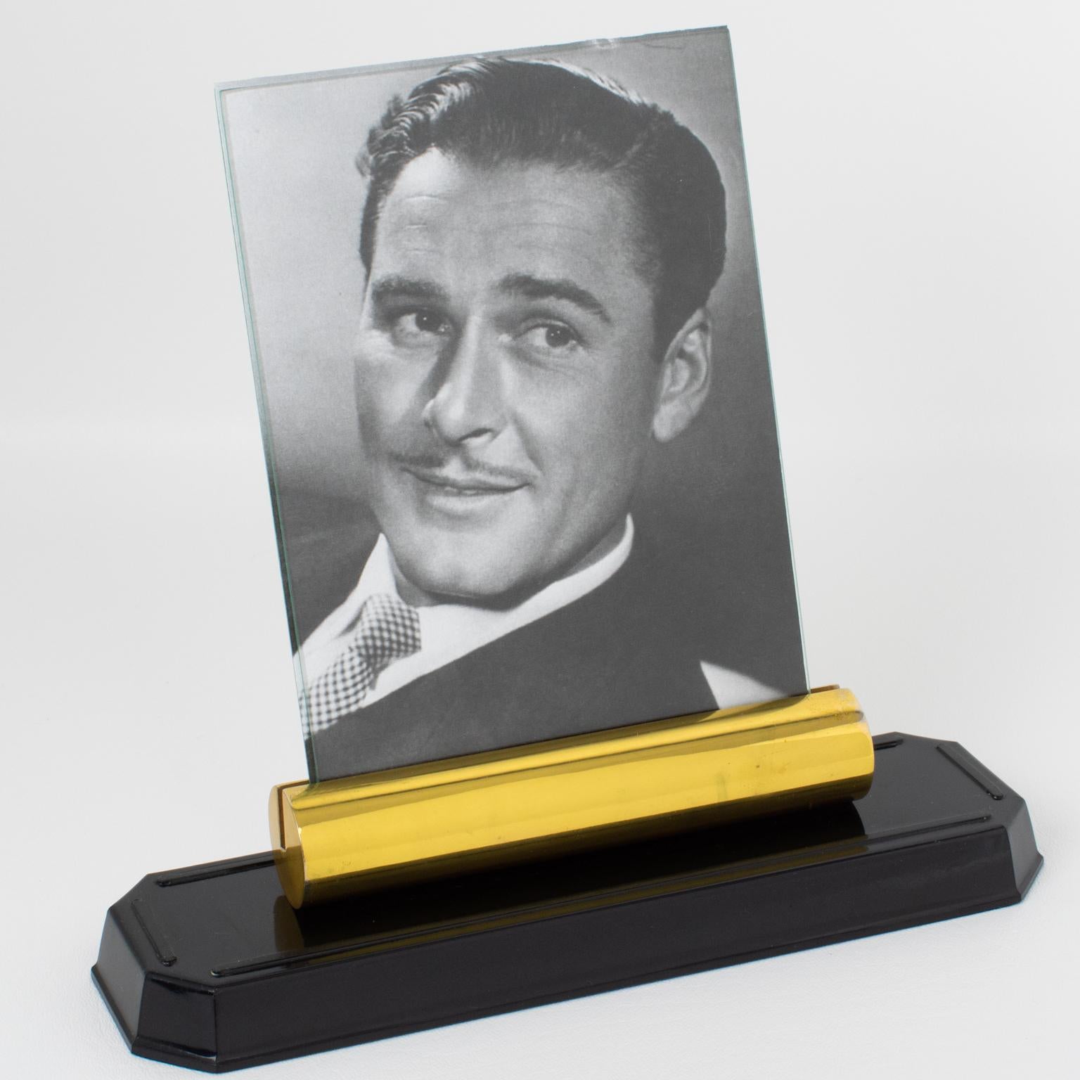 Made in France circa 1940, this stunning modernist Art Deco picture frame is built with brass and Bakelite. The piece boasts a stepped shiny brown Bakelite base topped with a thick gilded brass holder. The frame is complete with two glass sheets to