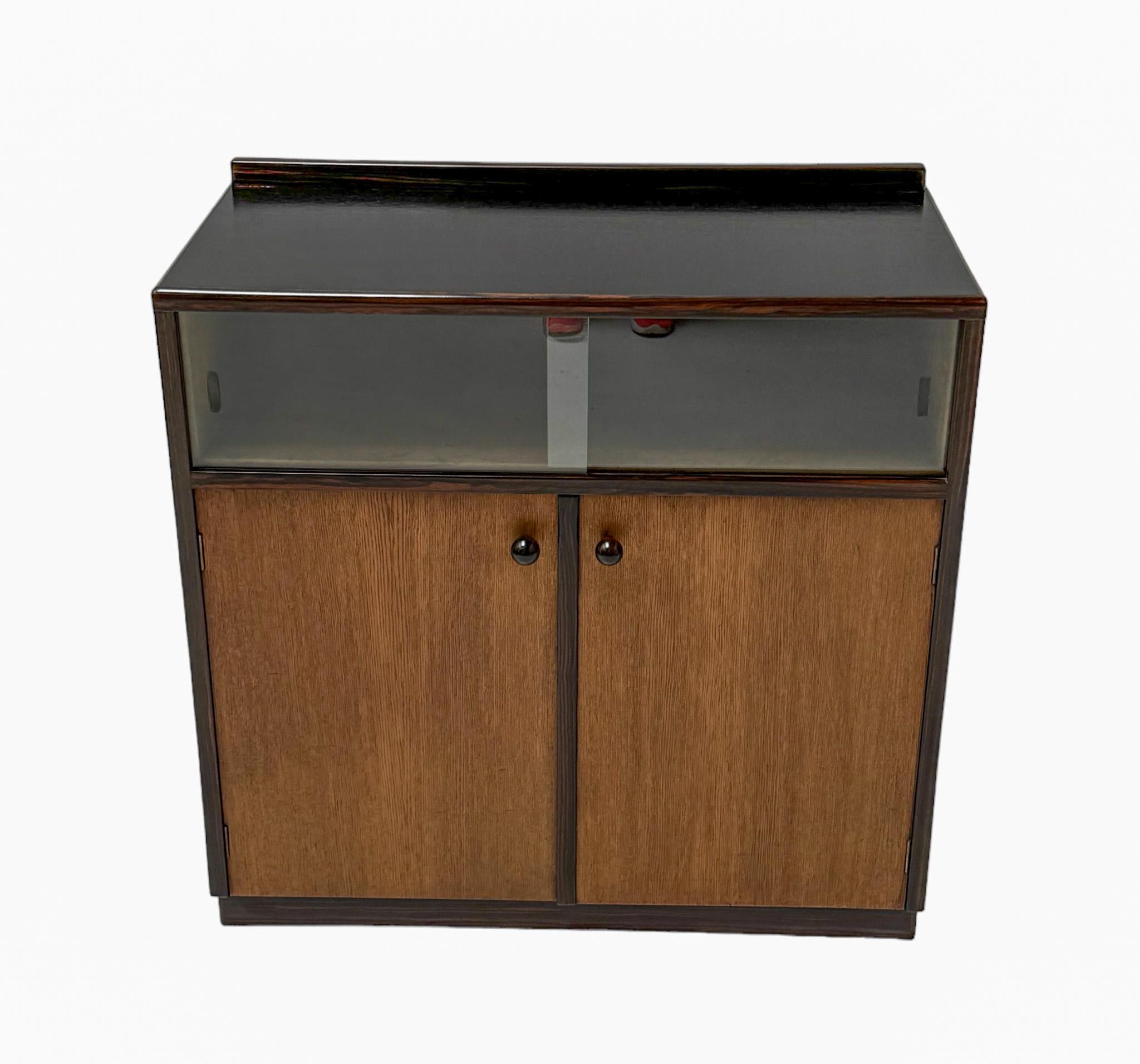 Atemberaubender und seltener Art Deco Modernist Schrank.
Entwurf von Anton Lucas für N.V. Meubelkunst Leiden.
Auffälliges niederländisches Design aus den 1920er Jahren.
Sockel aus massiver Eiche und Eichenfurnier mit zwei originalen Glasschiebetüren