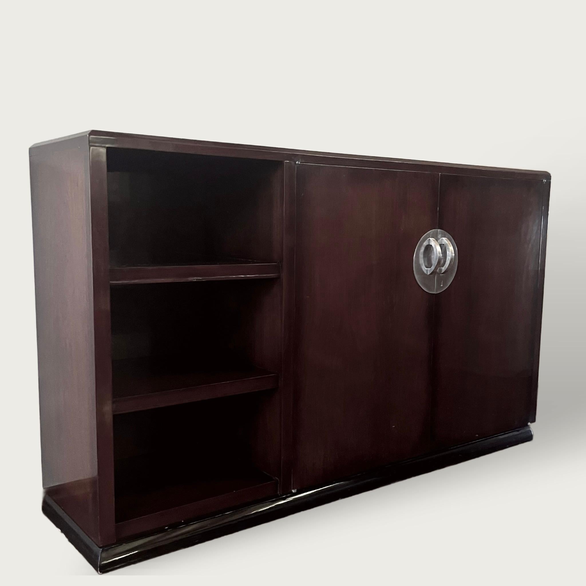 Credenza francese modernista, 1930 circa, in legno di palissandro su una base a plinto curvo laccata nera, tripla libreria a sinistra  e rifinita con una maniglia circolare sovradimensionata e minimale placcata in nichel. 