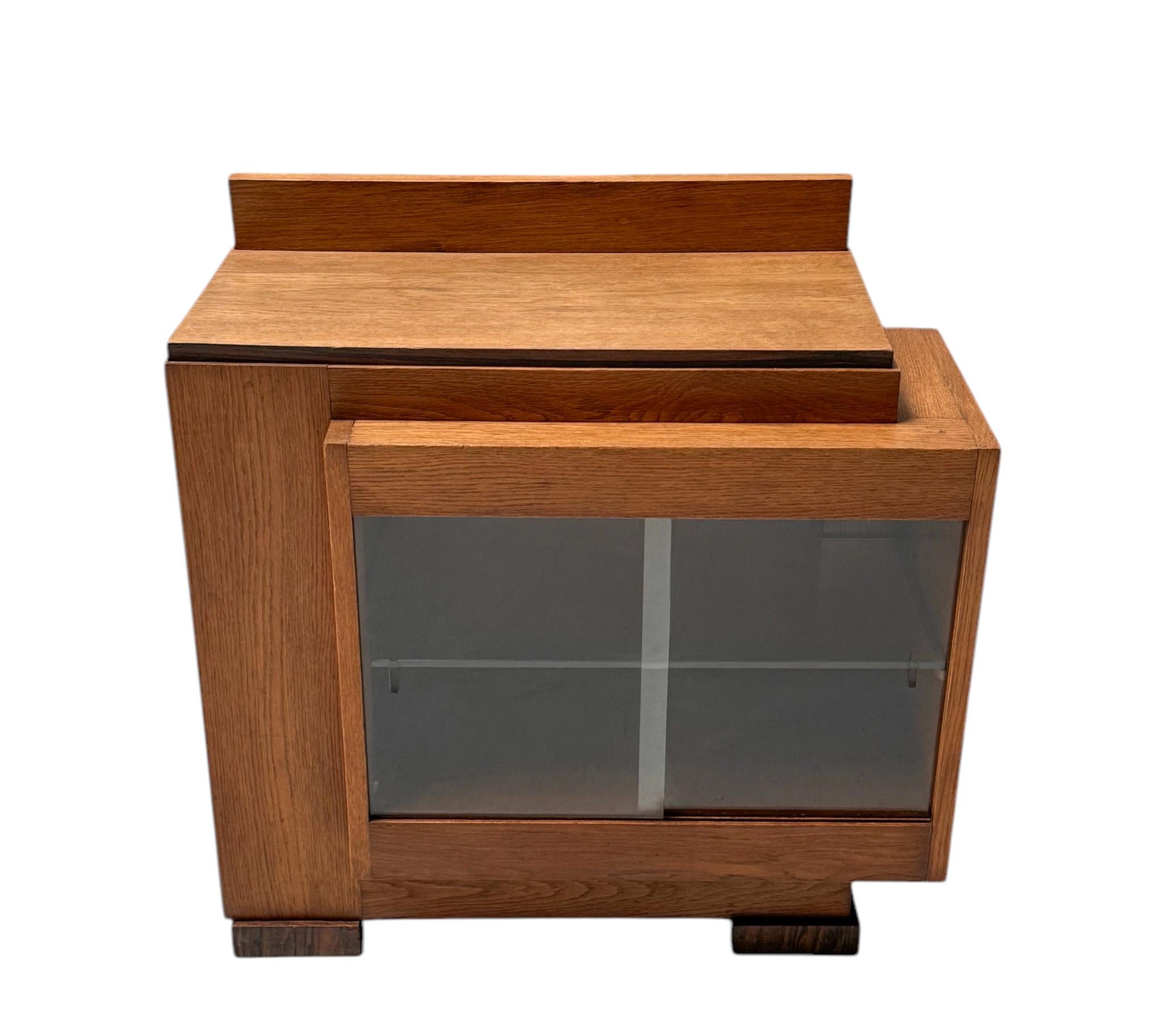 Stunning and rare Art Deco Modernist cabinet.
Striking Dutch design from the 1920s.
Solid oak base and top with original macassar ebony veneer at the legs.
Two original glass sliding doors and glass shelf inside.
This wonderful Art Deco Modernist