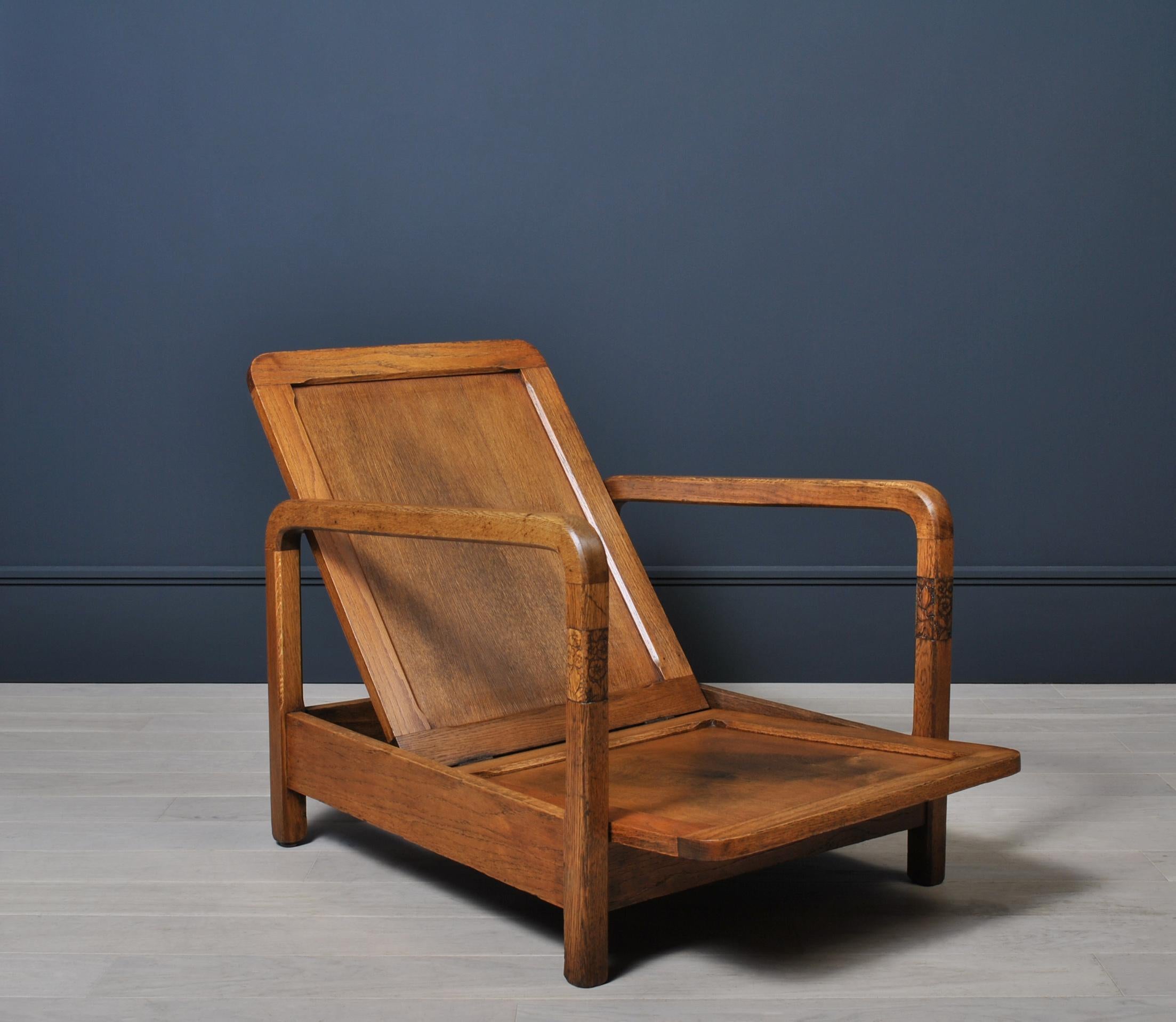 An early 20th century Art Deco Modernist chair. Circa 1920. Constructed from English Oak with beautiful little carved flower detail to the arm uprights. An extremely unusual and striking low profile chair. 
Please note that it is shown and sold