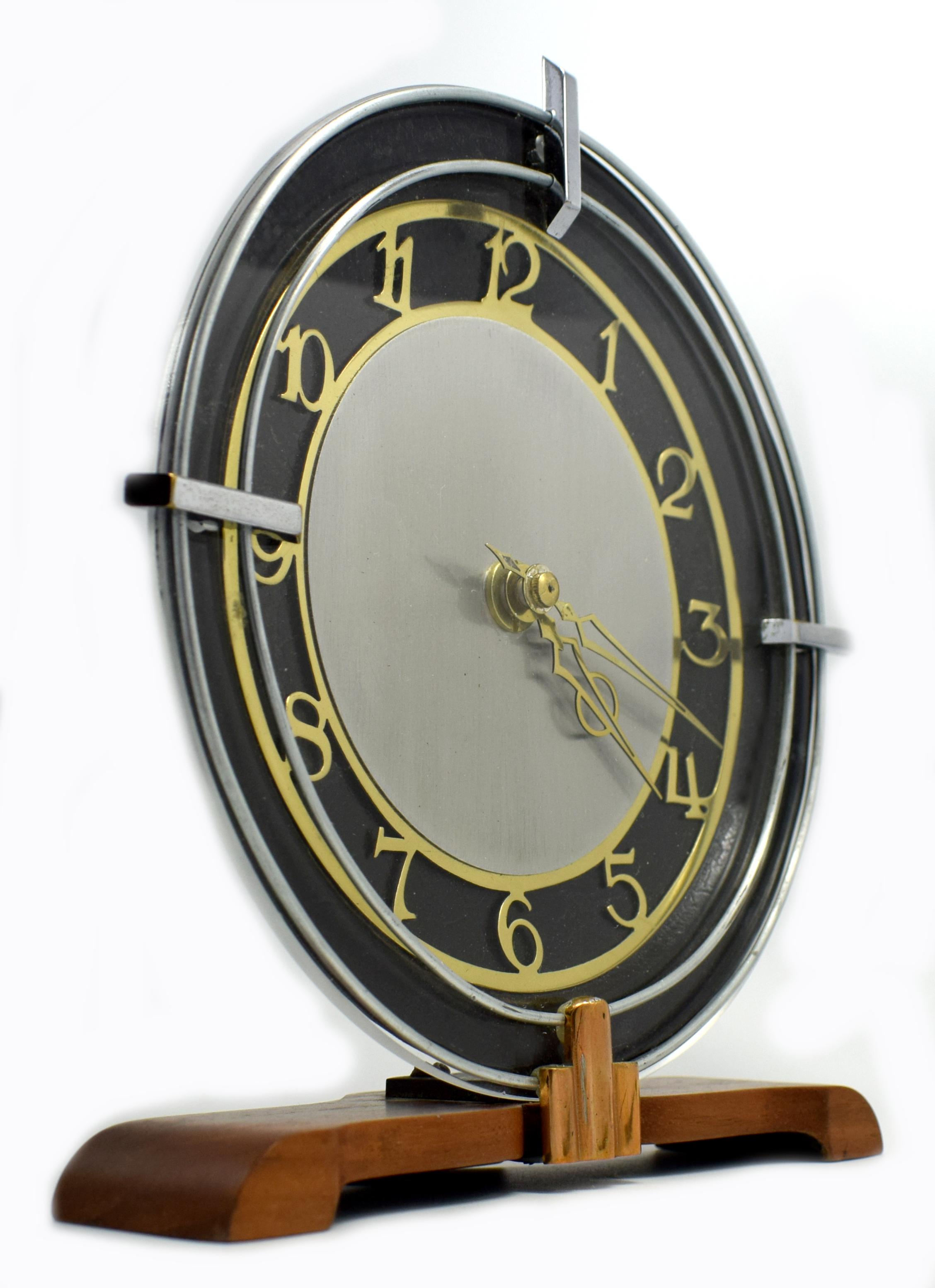 Originating from England and running on a converted quartz battery movement so will work on all continents so no winding required. This Art Deco clock has a mix of materials, from a beechwood base, ebonized accents, brass fretted numerals and chrome