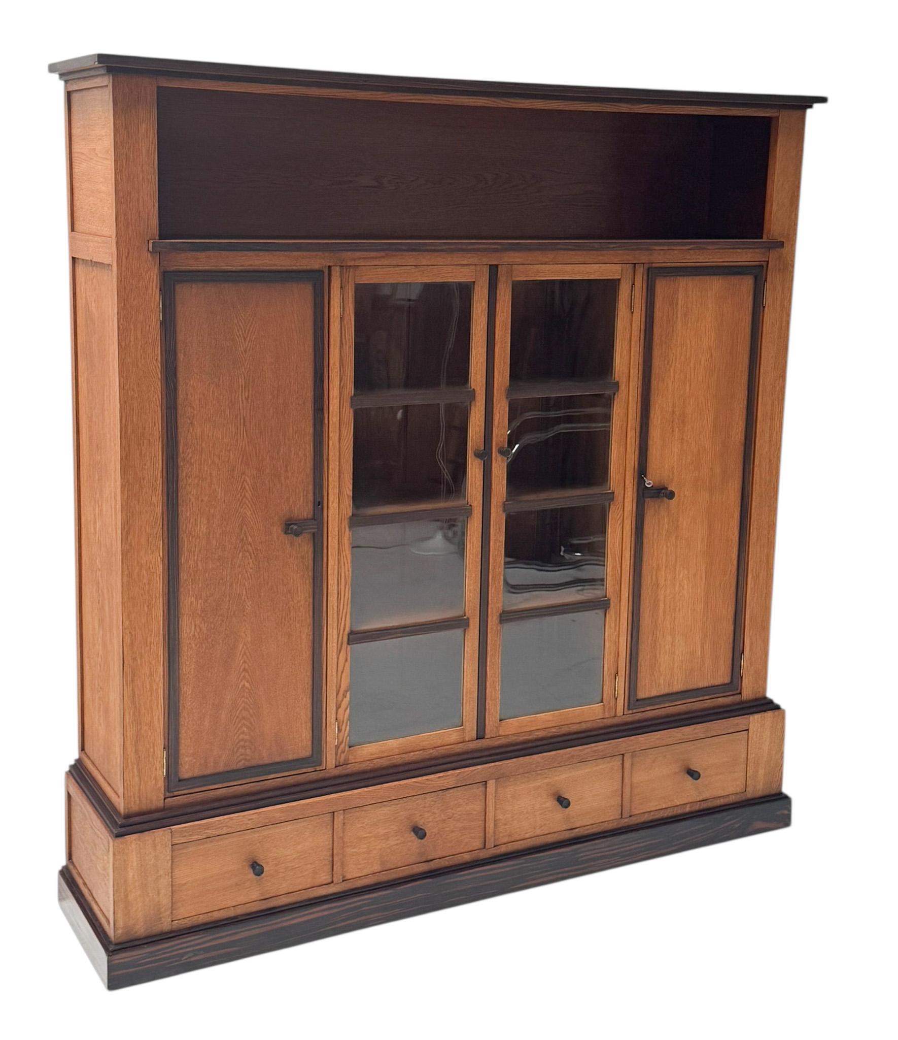 Magnifique et rare bibliothèque moderniste Art Déco à quatre portes.
Un design néerlandais saisissant des années 1920.
Base en chêne massif avec boutons d'origine en ébène de macassar massif sur les quatre portes et les quatre tiroirs.
Neuf étagères