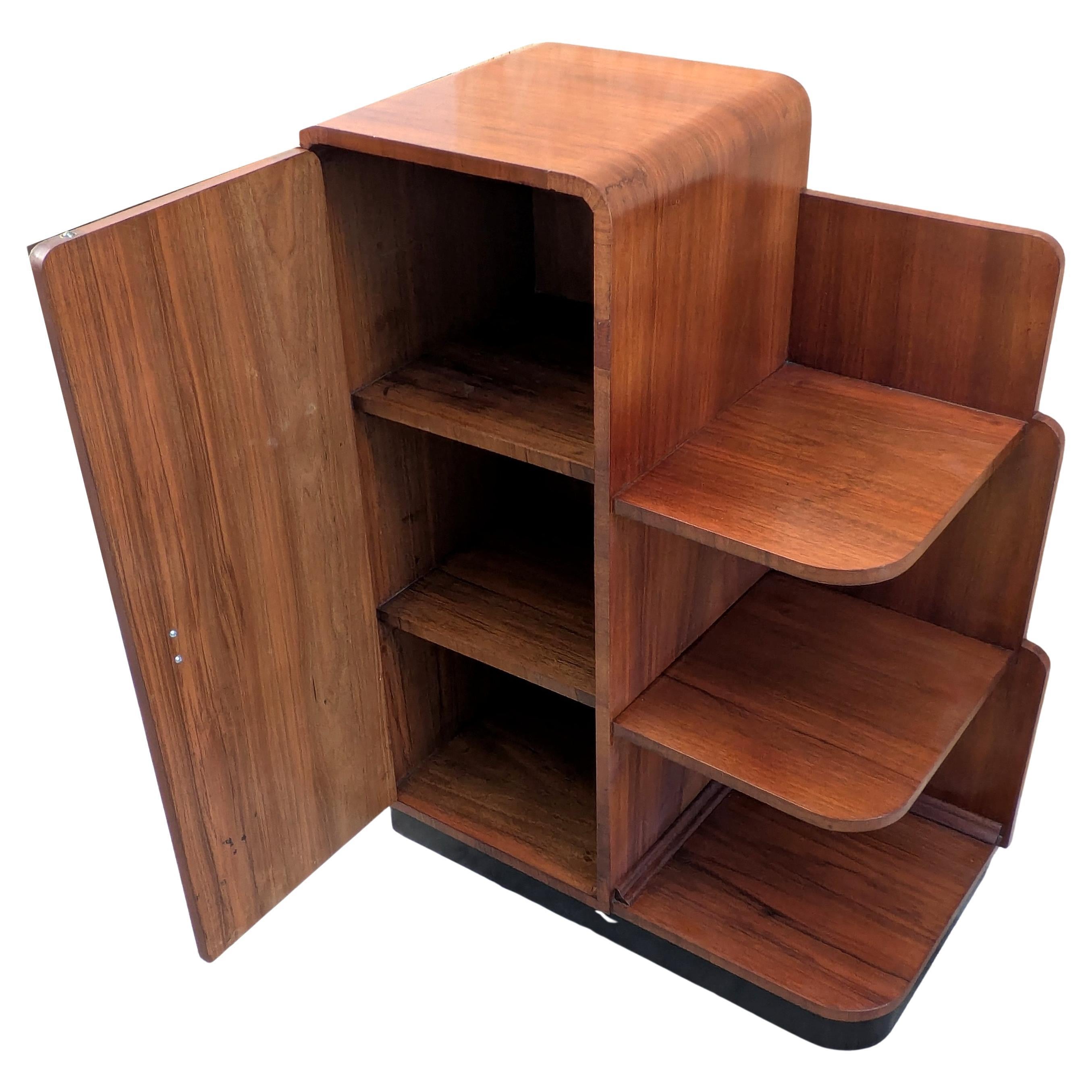 Te presentamos esta elegante e inusual mesa auxiliar modernista Art Decó de 1930. Tamaño ideal para el uso actual. Armario de nogal de 1930 muy atractivo, bellamente labrado, con estantes que se abren. El interior tiene más estanterías, la puerta se