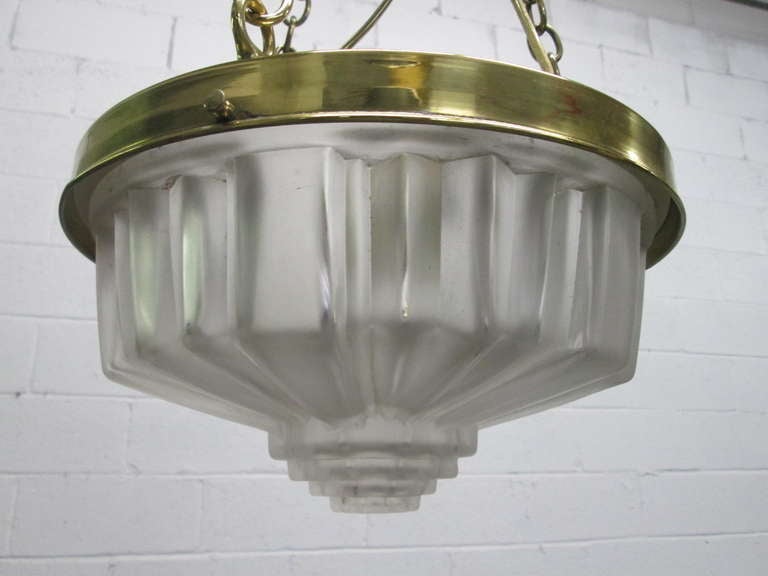 Art Deco molded glass hanging light fixture. Has brass trim with hanging links and cap.
