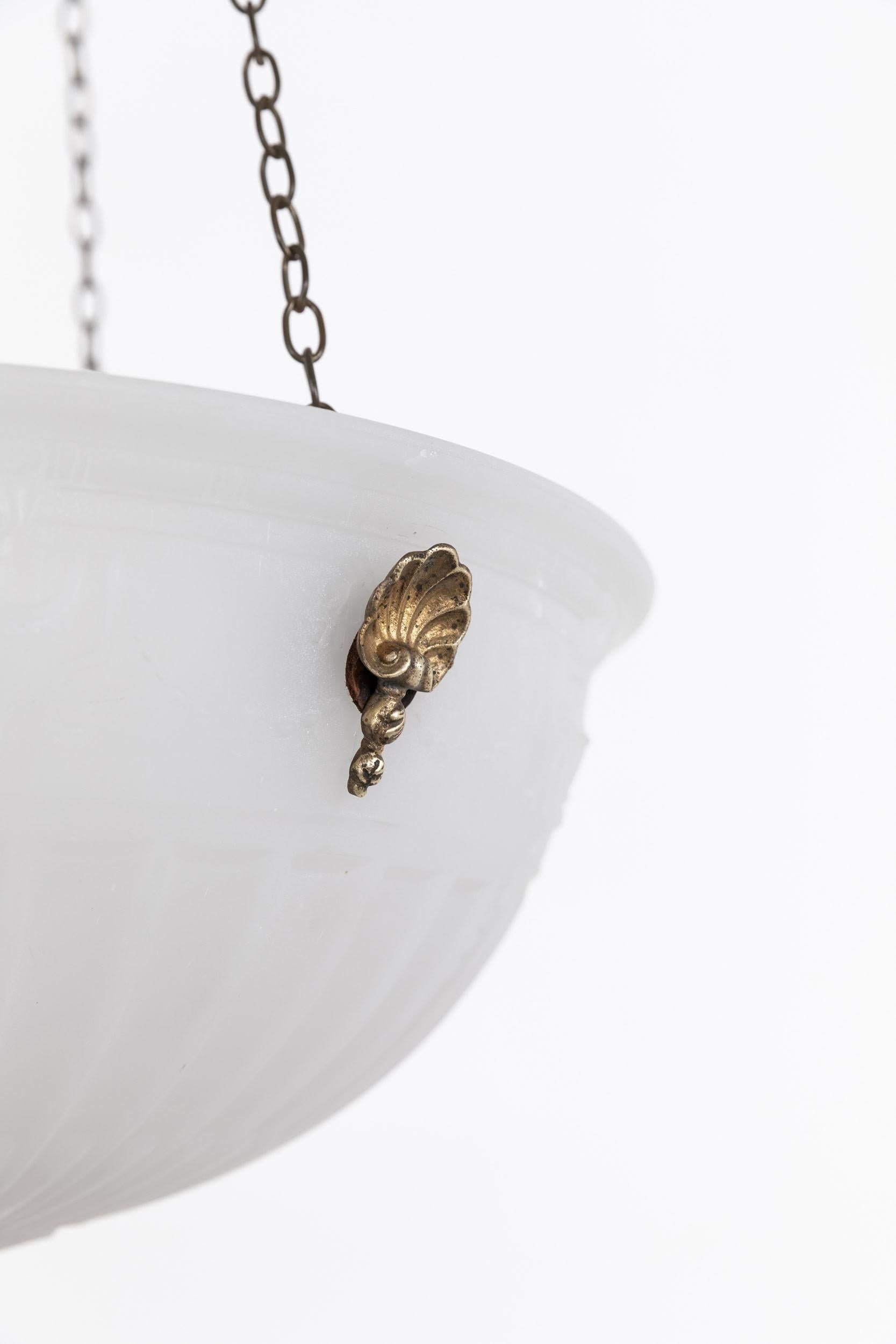 

An elegant moonstone plafonnier pendant light. c.1930

Thick pressed frosted moonstone glass of fluted design with lotus flower decoration. Complete with integral decorative gilt hooks, chain and ceiling hook. Chains can be shortened to suit