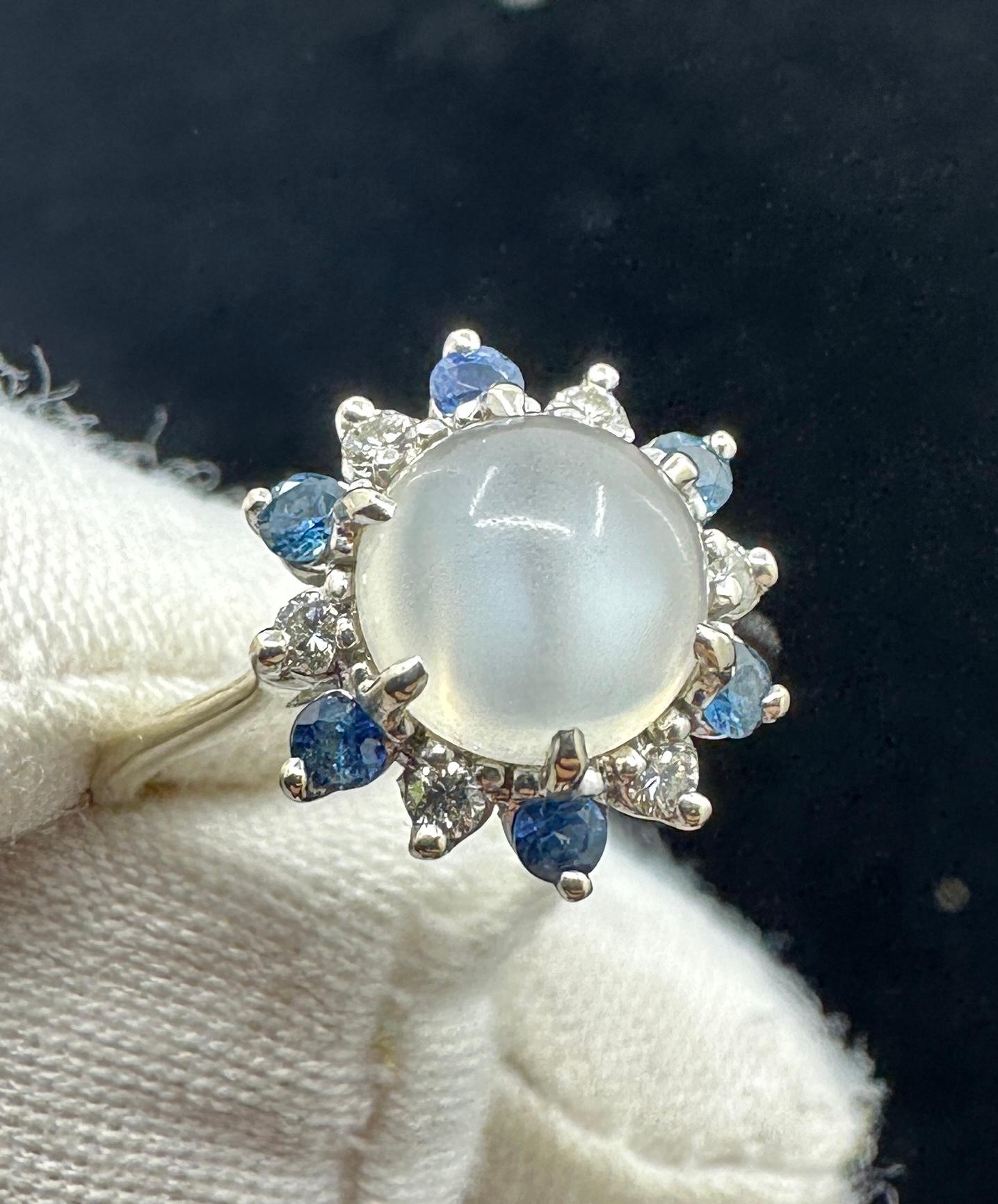 Gönnen Sie sich einen Mondstein-Saphir-Diamant-Ring aus der Art Déco-Zeit von großer Schönheit in 14 Karat Weißgold.  Der zentrale runde Cabochon im Kuppelschliff des Mondsteins ist einfach göttlich.  Die blaue Adulareszenz im Inneren des Mondsteins